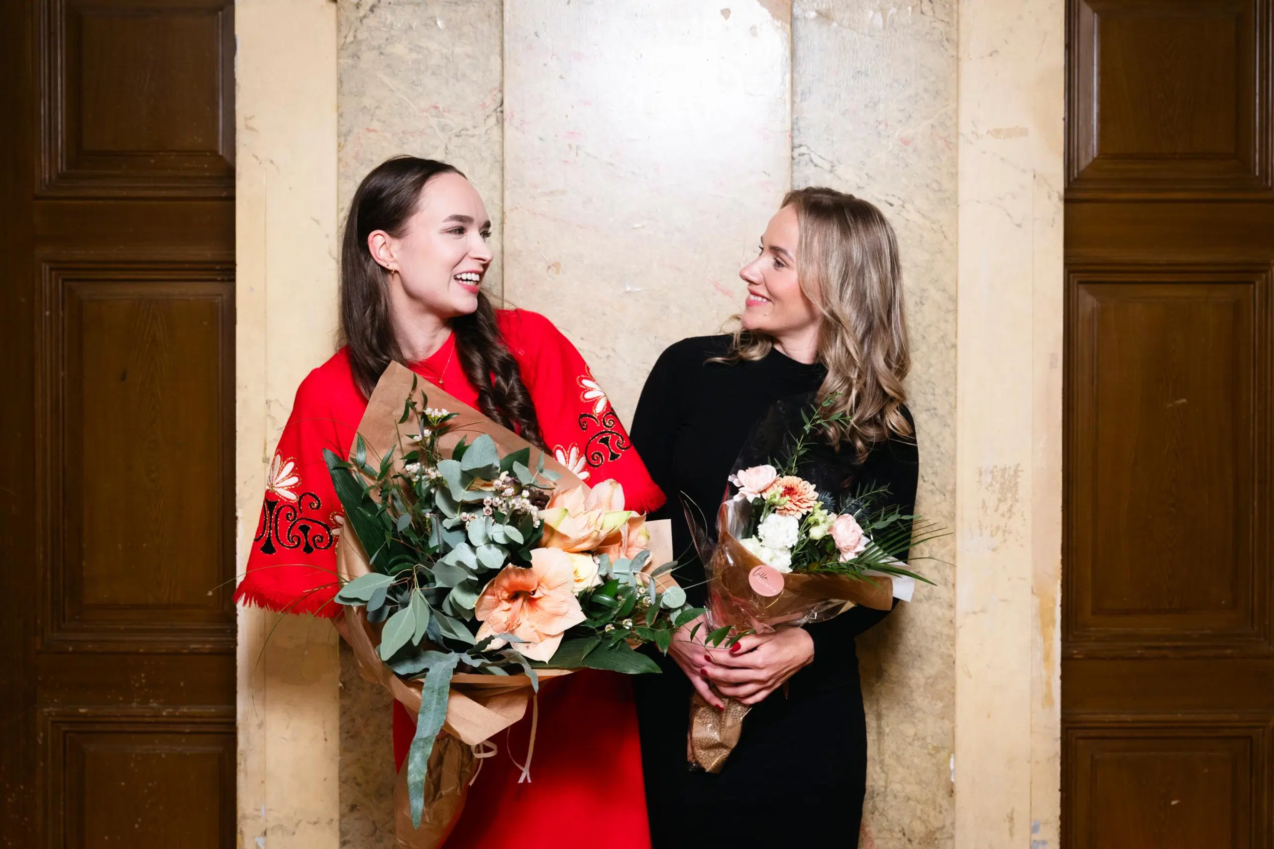 Anemone Aaltonen ja Elina Leskinen katsovat toisiaan. Molemmilla on käsissään kukkakimppu.