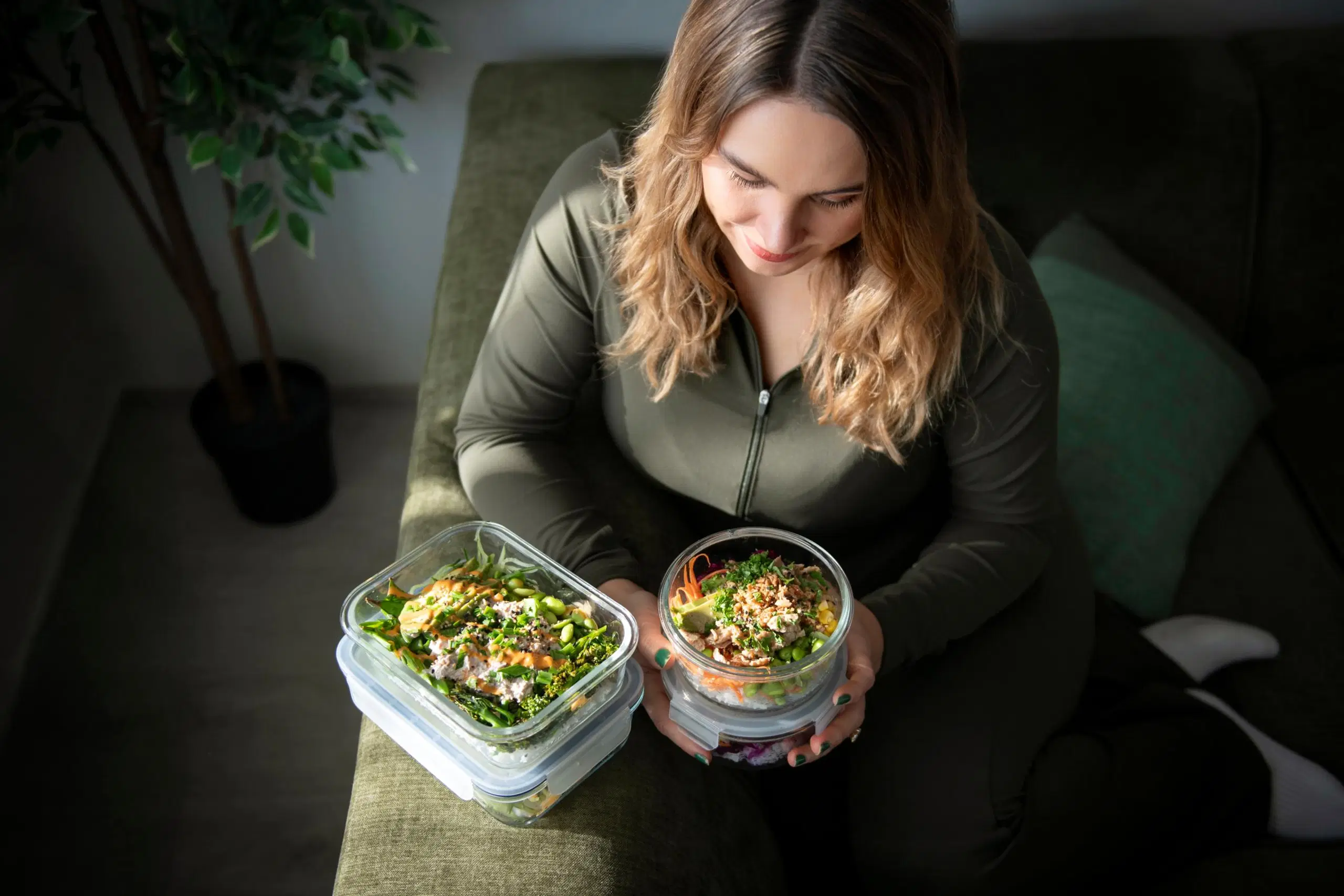 Eveliina Uosukainen istuu sohvalla ja esittelee kahta ruoka-annosta.