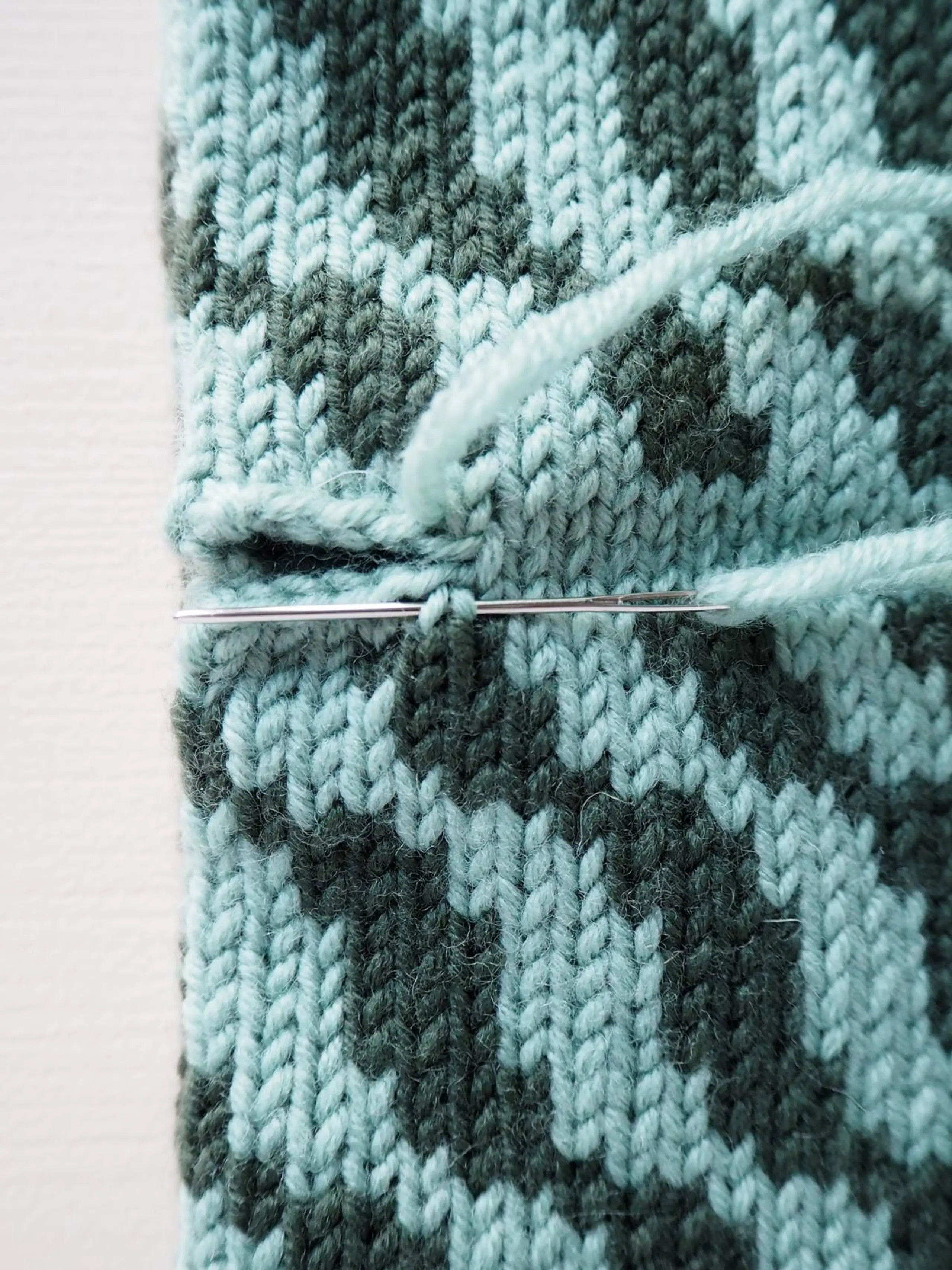 Lähikuva neulepannan päiden yhdistämisen toisesta vaiheesta.