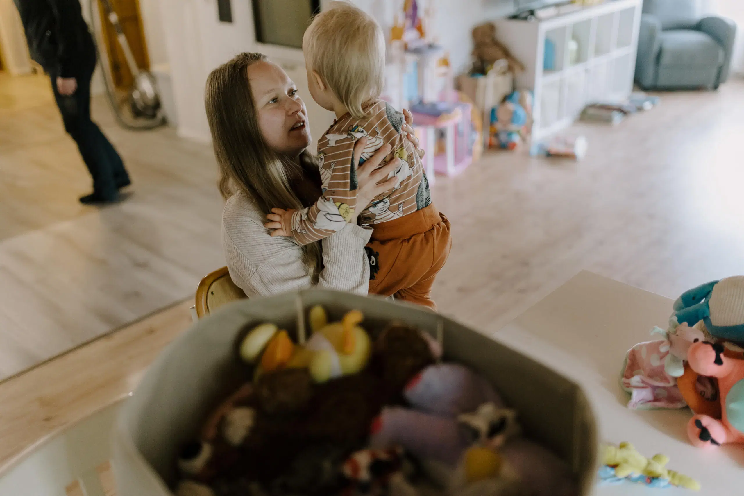 Nainen pitää lasta sylissään, paljon tavaroita ympärillä