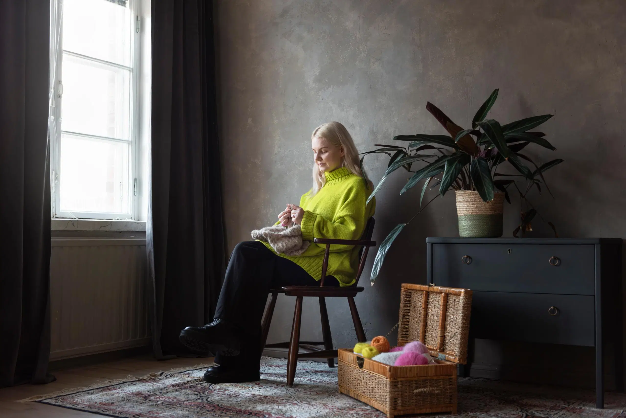 Elsi Vankka istuu tuolissa ja neuloo.