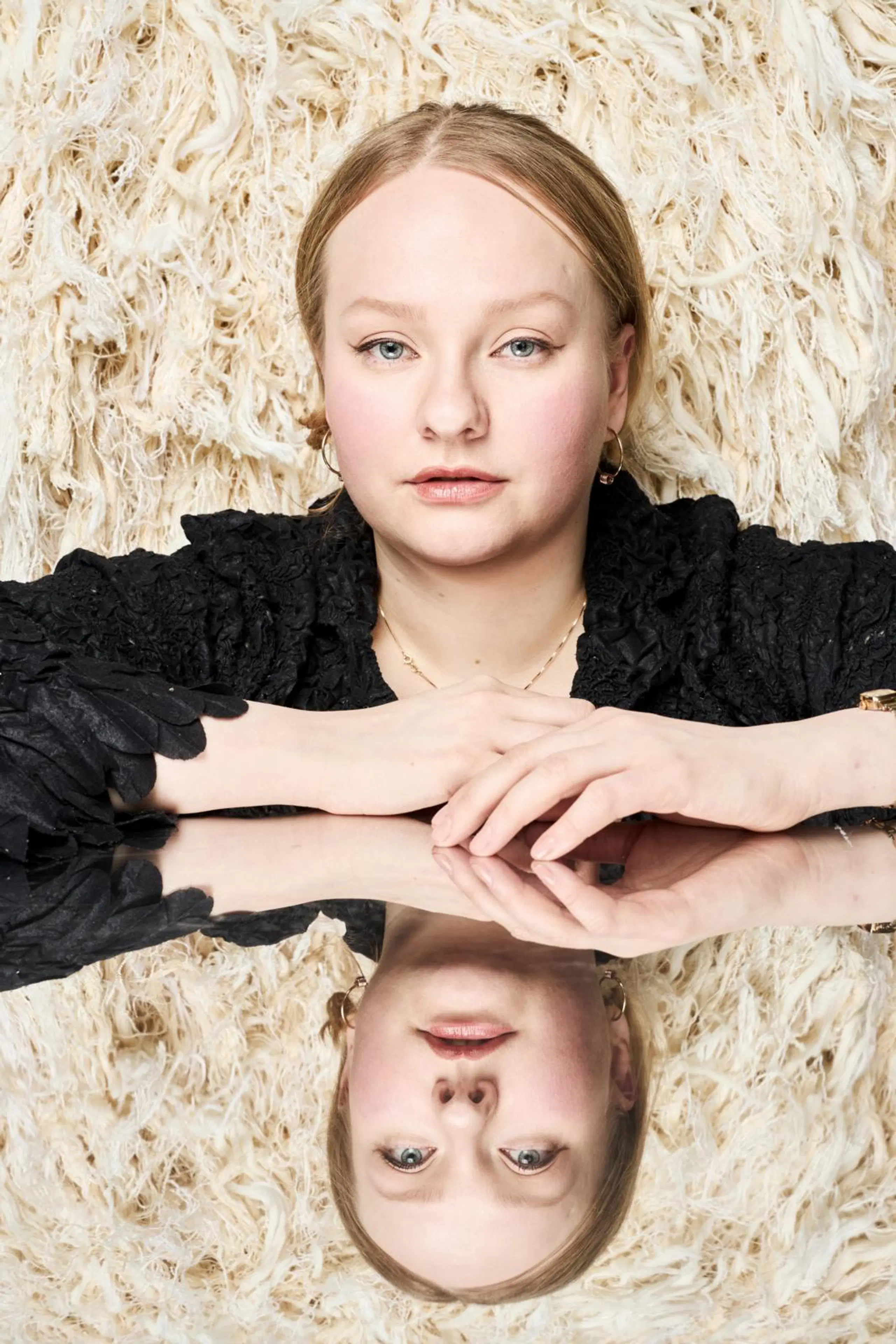 Enni Lähderinne katsoo kameraan. Taustalla hänen sunnittelemansa ryiykankainen mekko.