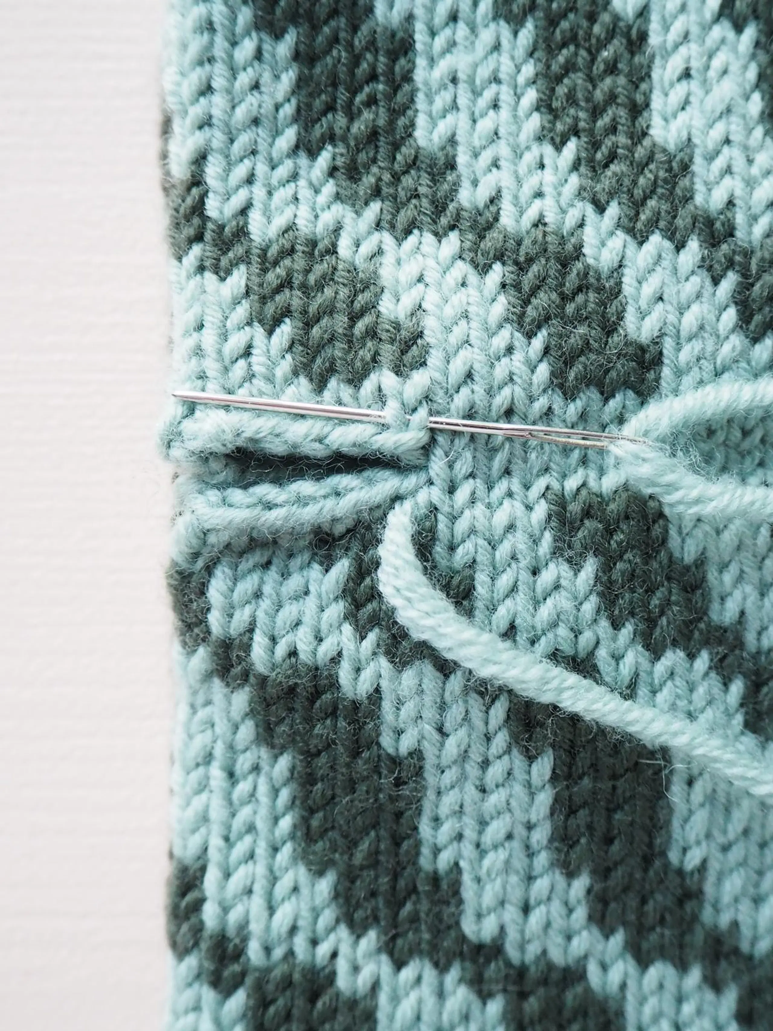 Lähikuva neulepannan päiden yhdistämisen ensimmäisestä vaiheesta.