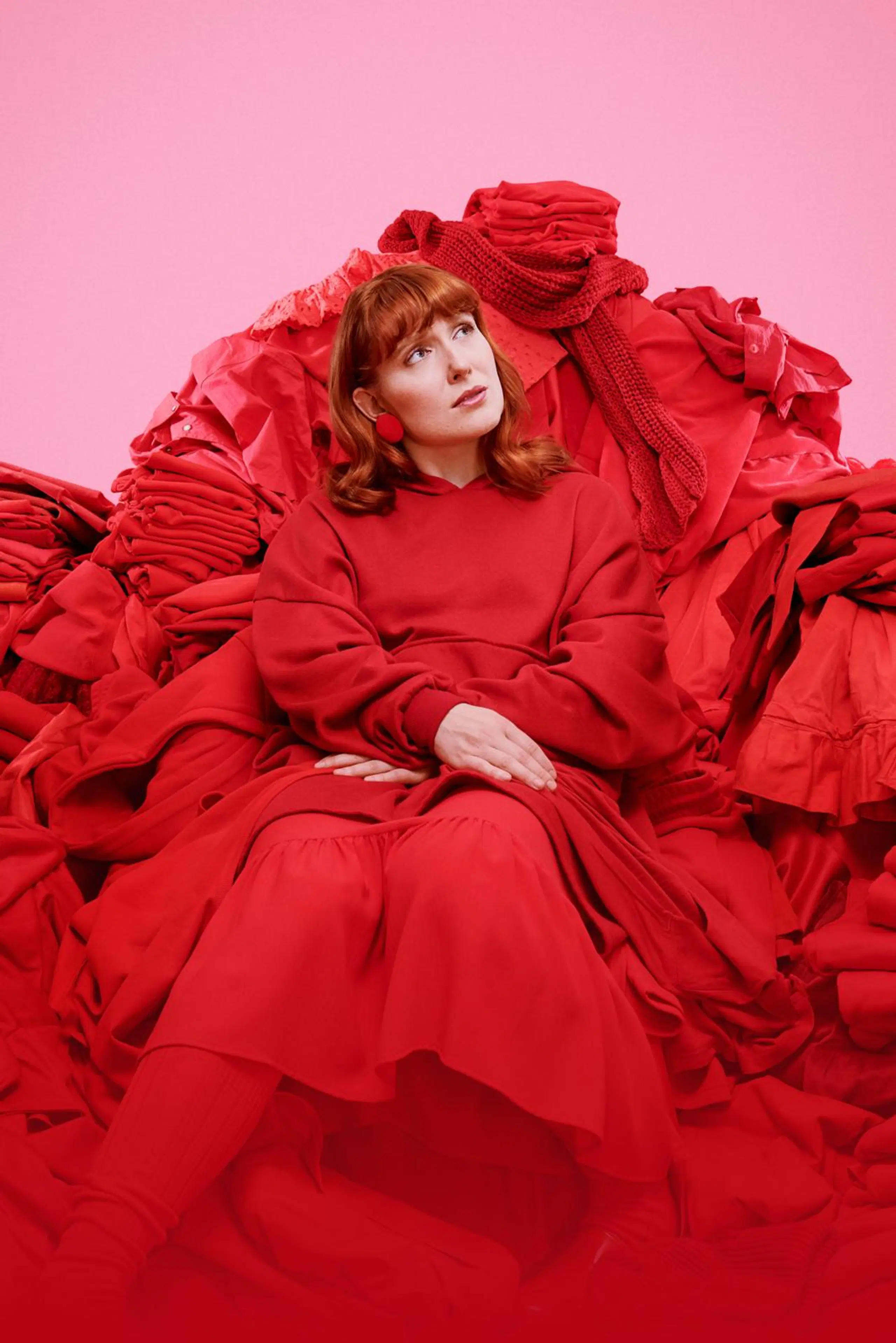 Nainen istuu punaisessa vaatekasassa