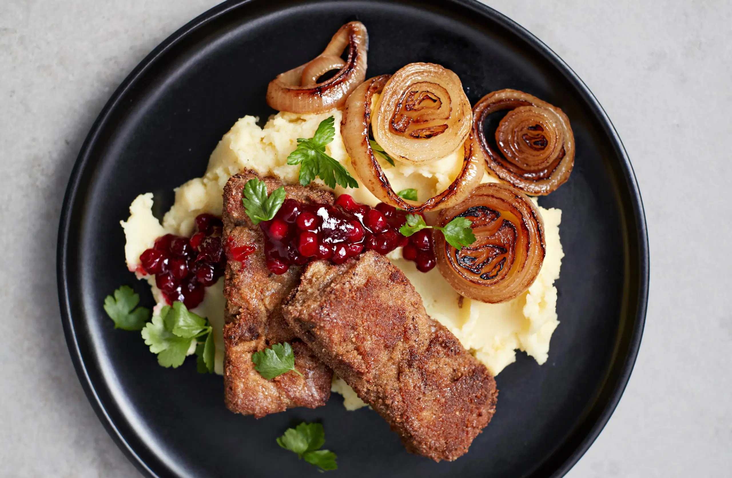 Maksalaatikkopihvit perunamuusin, paistetun sipulin ja puolukkahillon kanssa