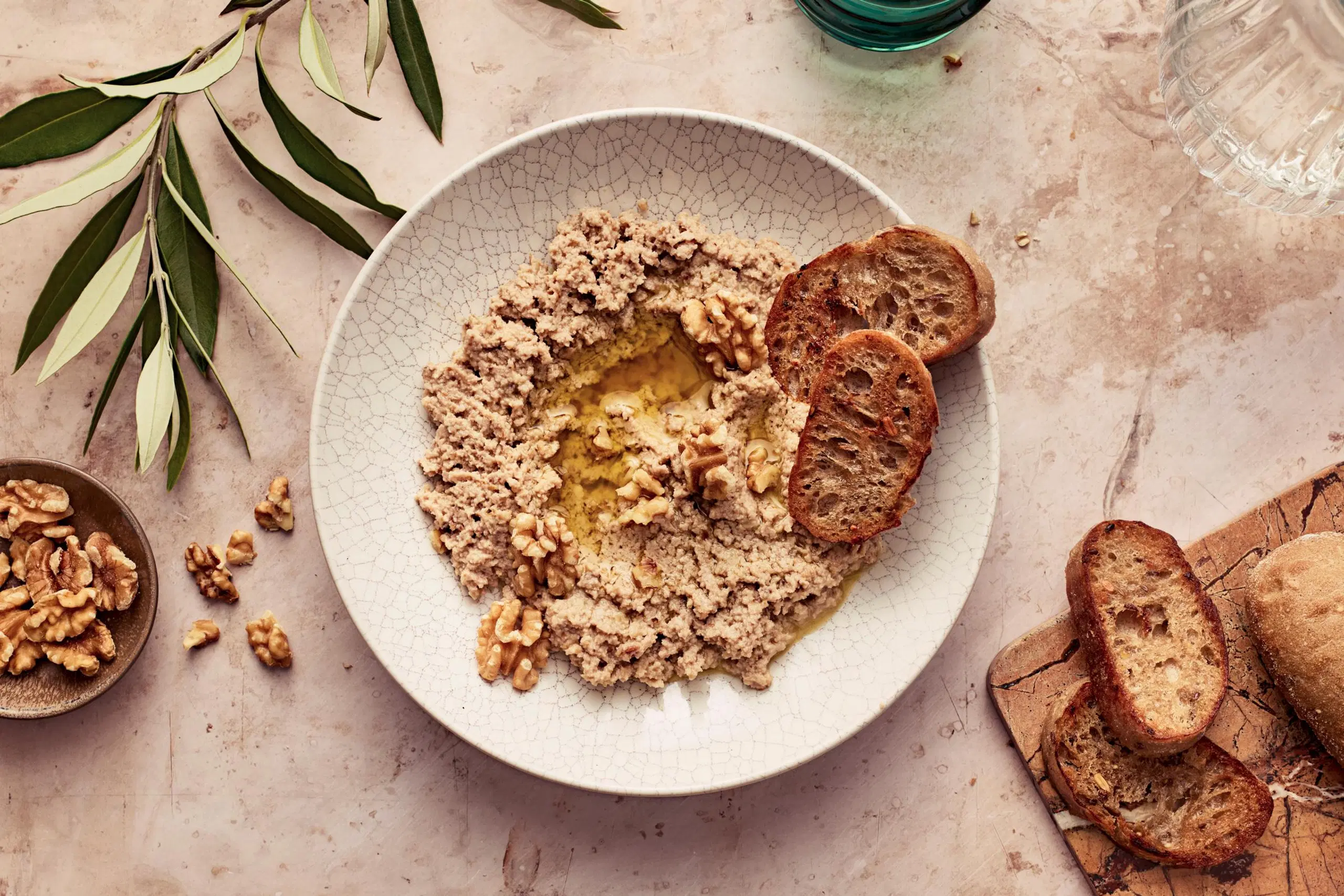 Saksanpähkinätahnaa lautasella. Paahdettua leipää vieressä.