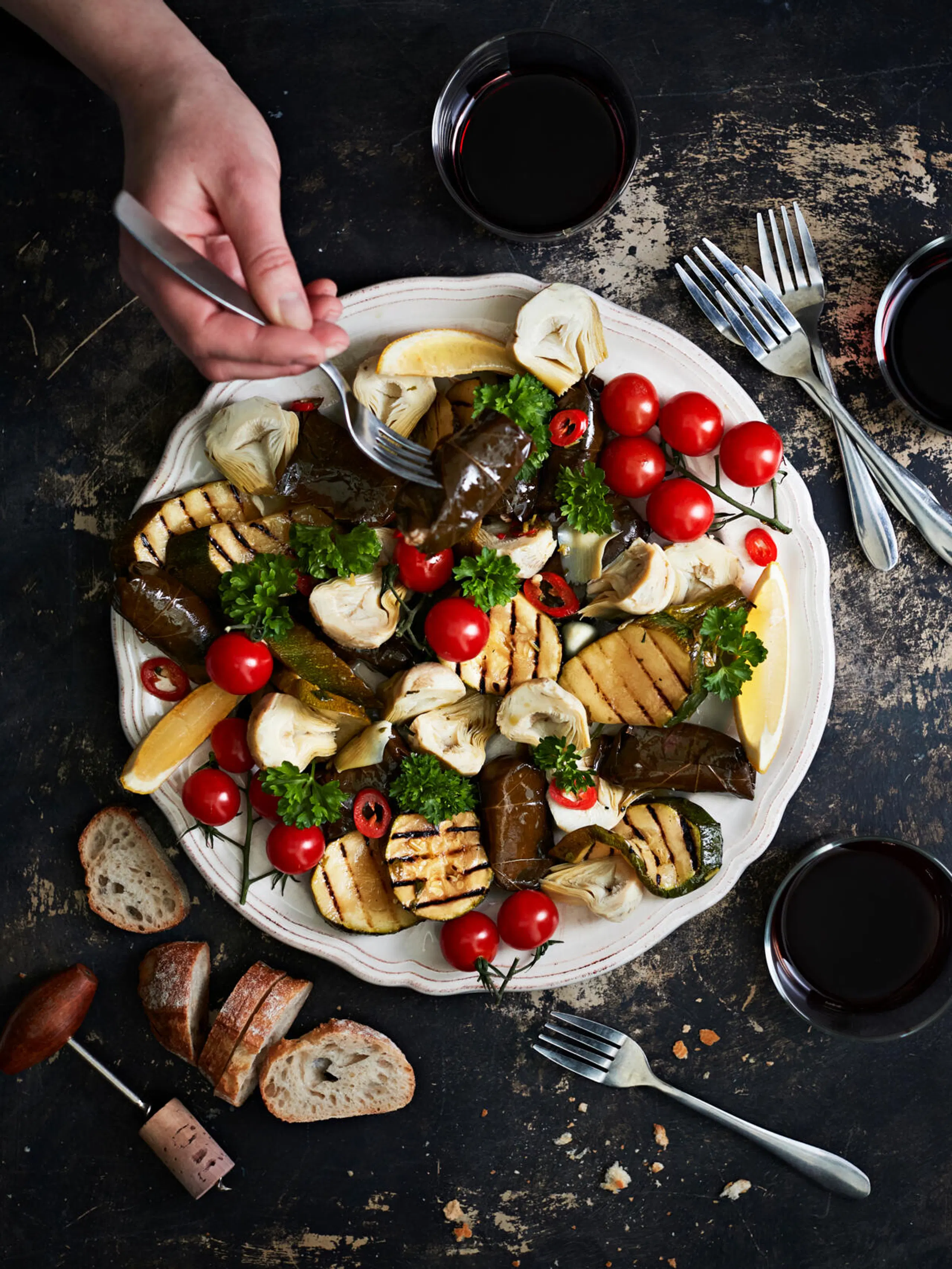 Välimerellinen antipastolautanen, jossa grillattua kesäkurpitsaa, kirsikkatomaatteja, artisokkaa ja viininlehtikääryleitä.