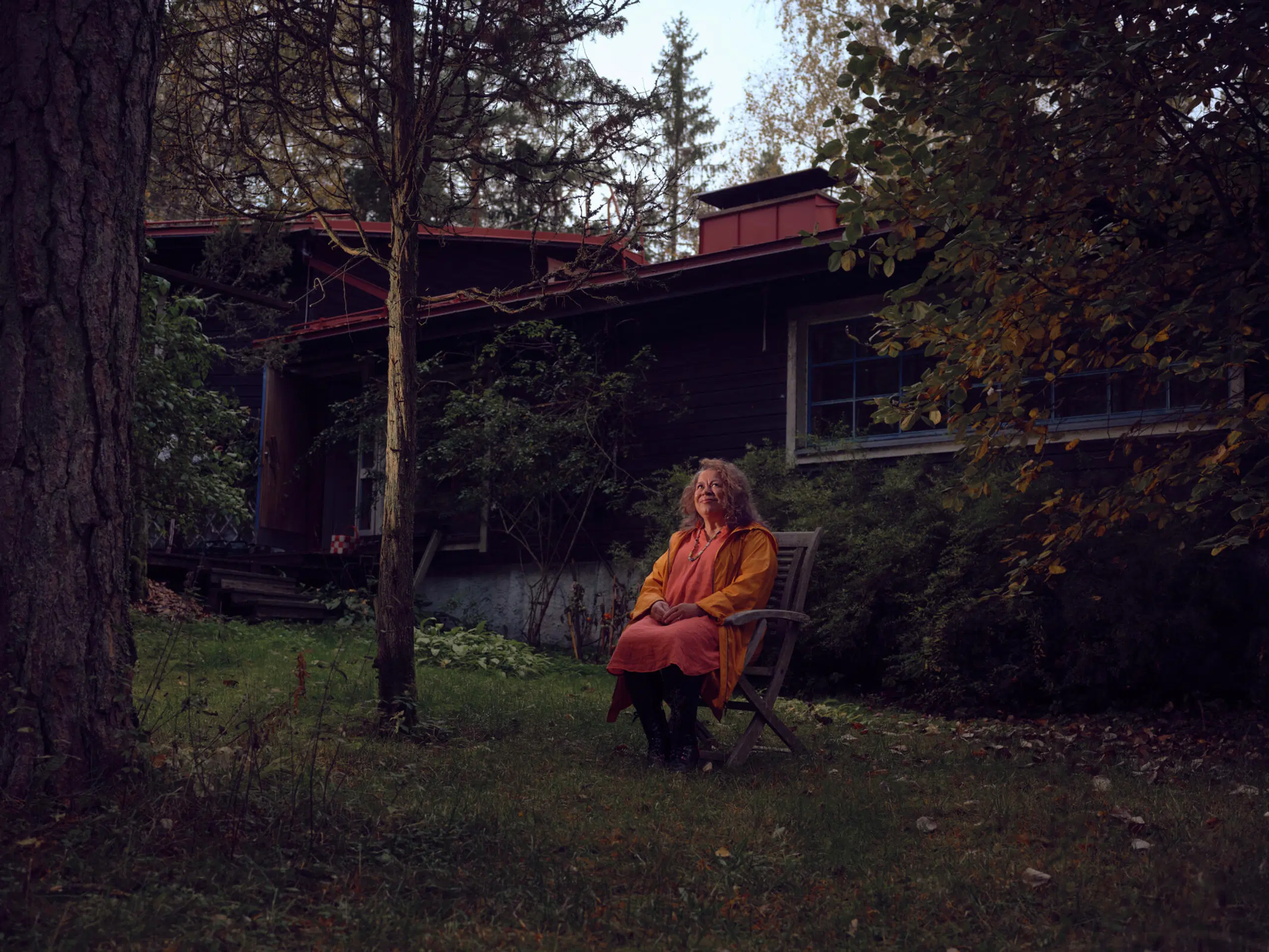 Kirjailija Leena Lehtolainen istuu kotinsa pihalla.