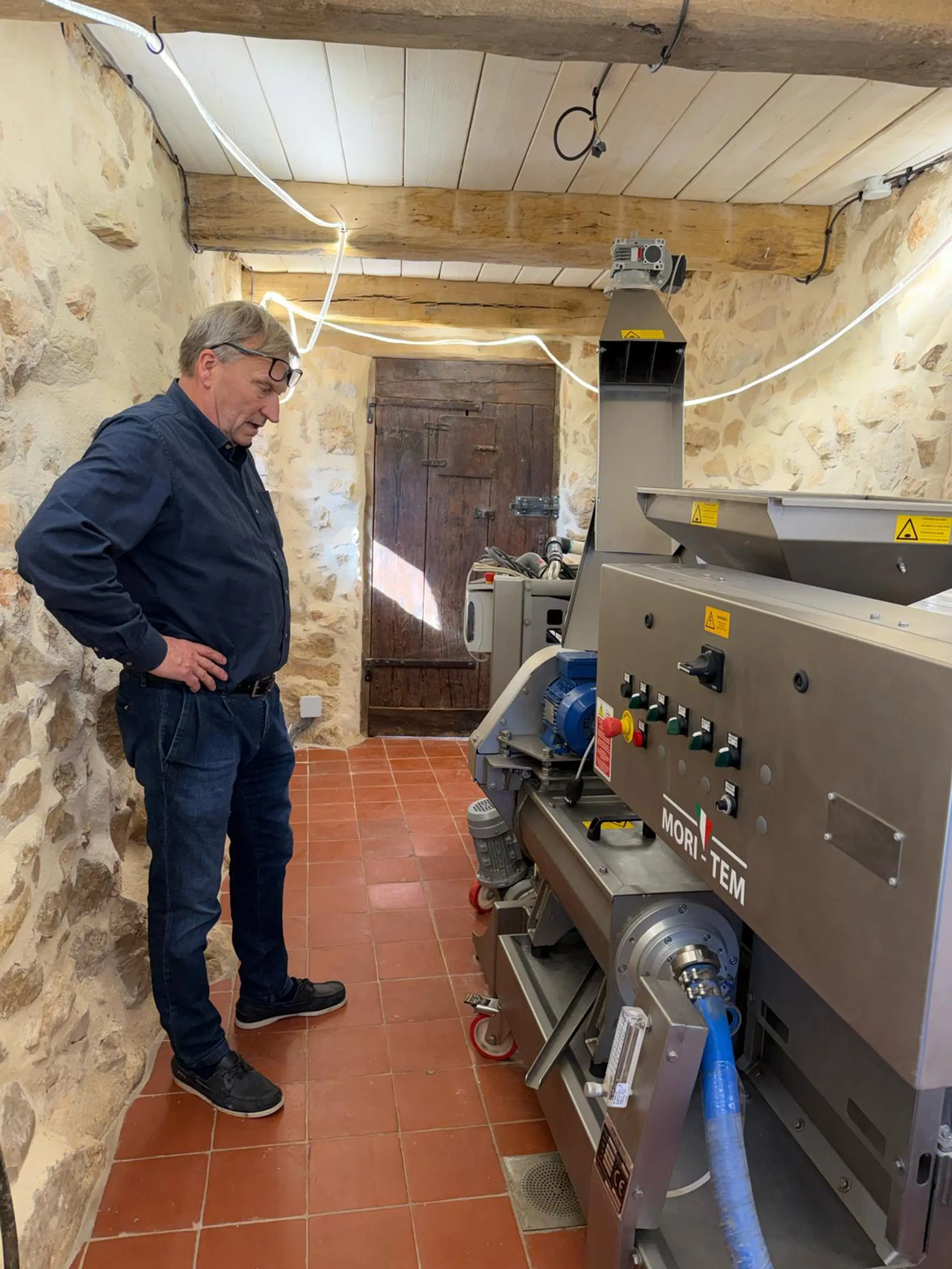 Mies seisoo öljypuristimen vieressä