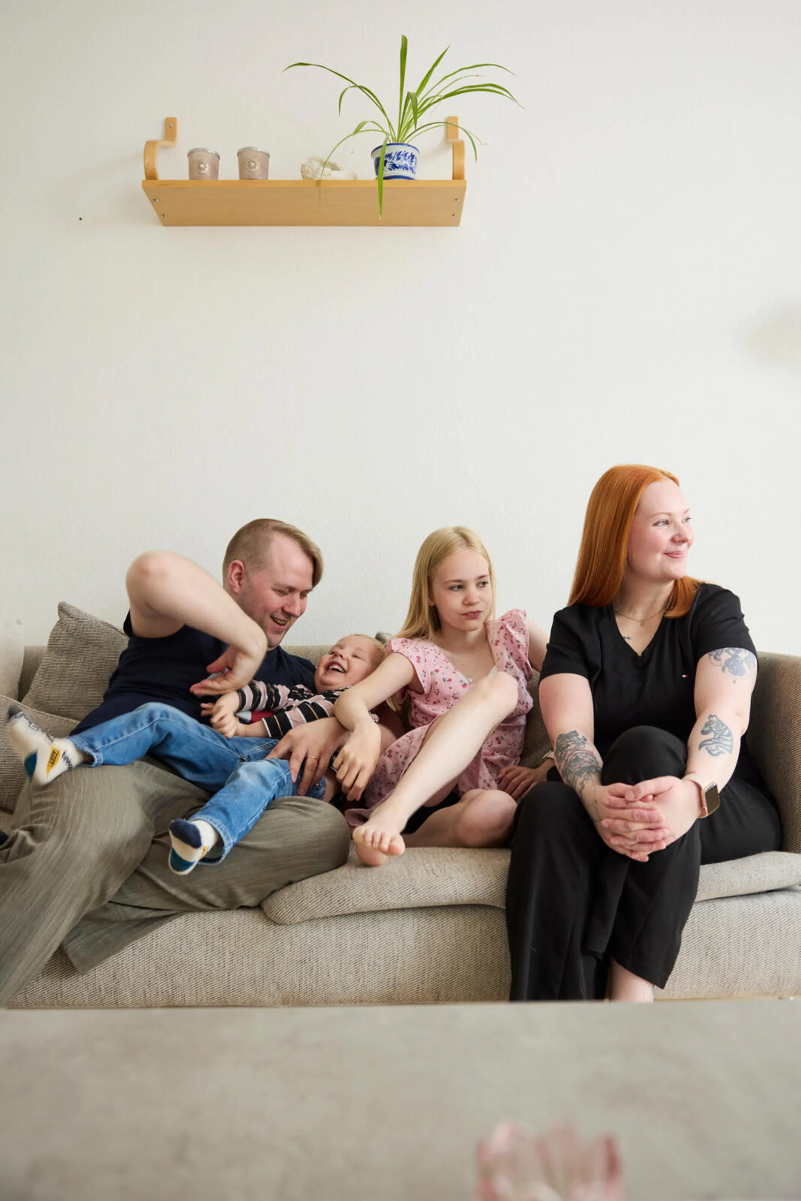 Anni ja Jussi Tuomola istuvat iloisina kahden lapsensa kanssa sohvalla.