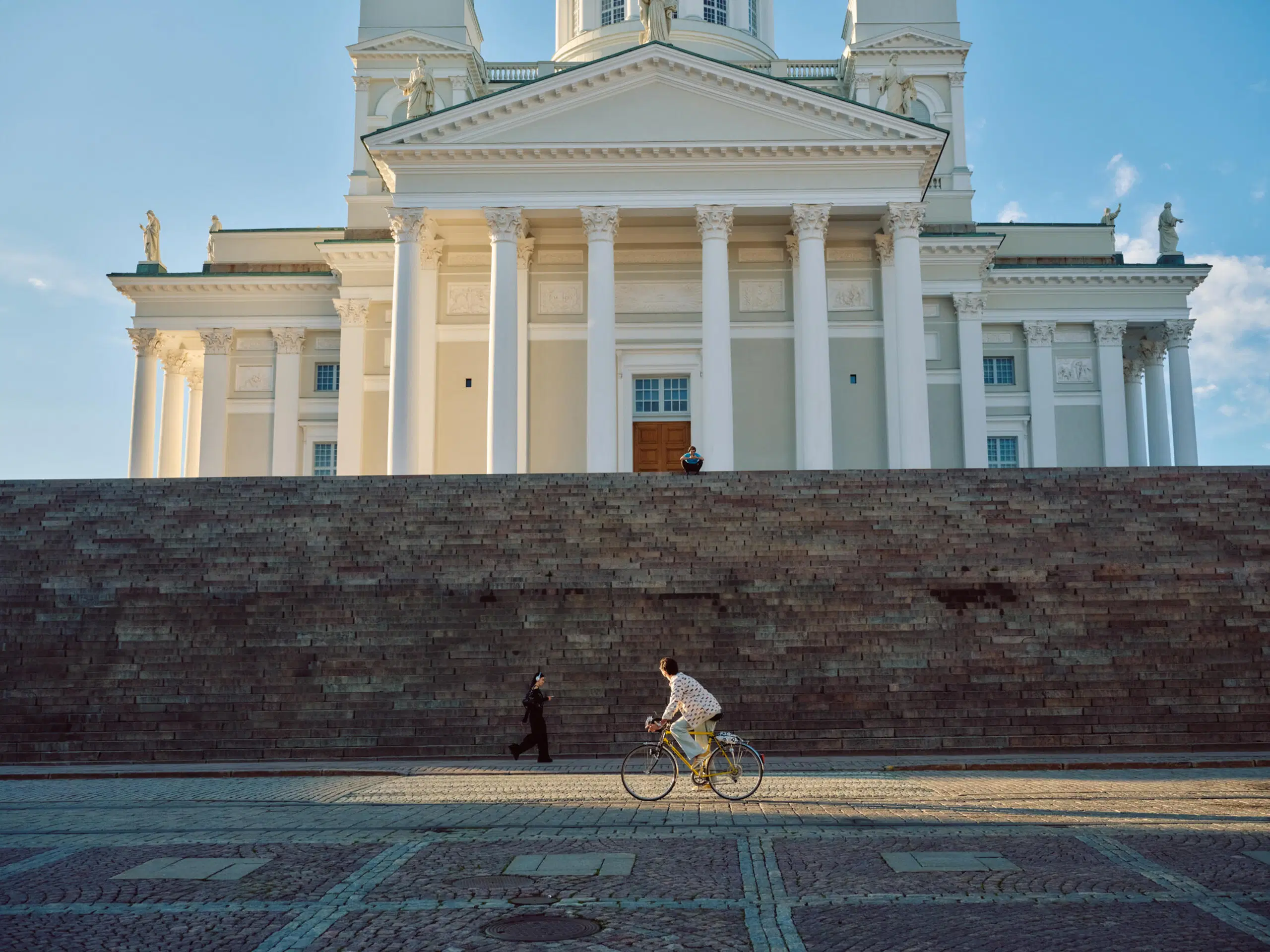 Henkilö pyöräilee Senaatintorilla Helsingissä