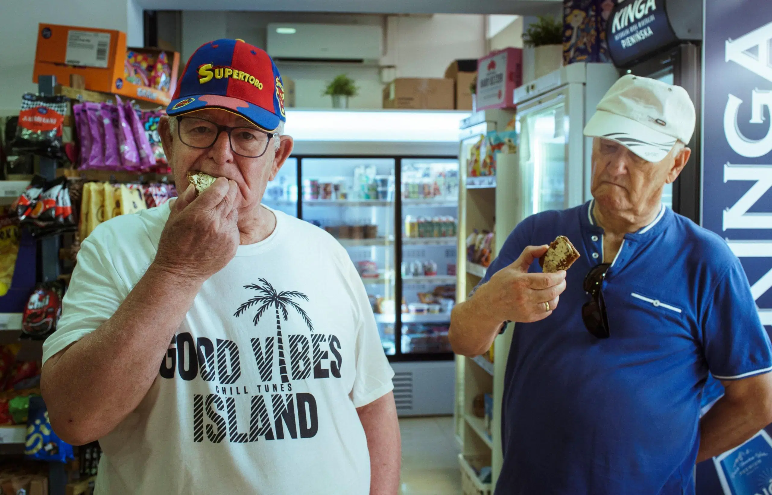 Kaksi lippalakkipäistä miestä maistelee ruokaa kaupassa