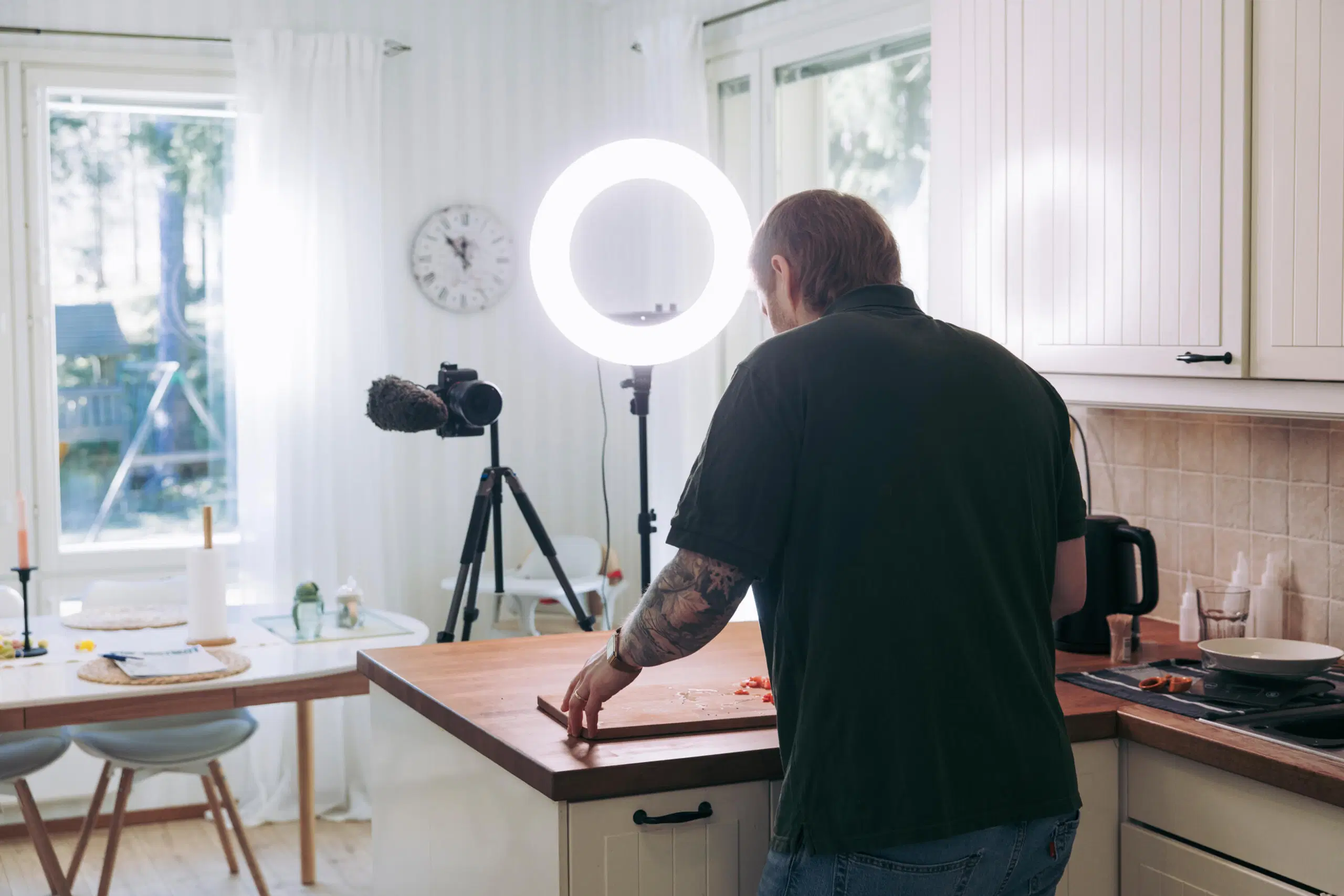 Tommi Manninen kokkaa keittiössä kameran ja rengasvalon kuvatessa häntä.