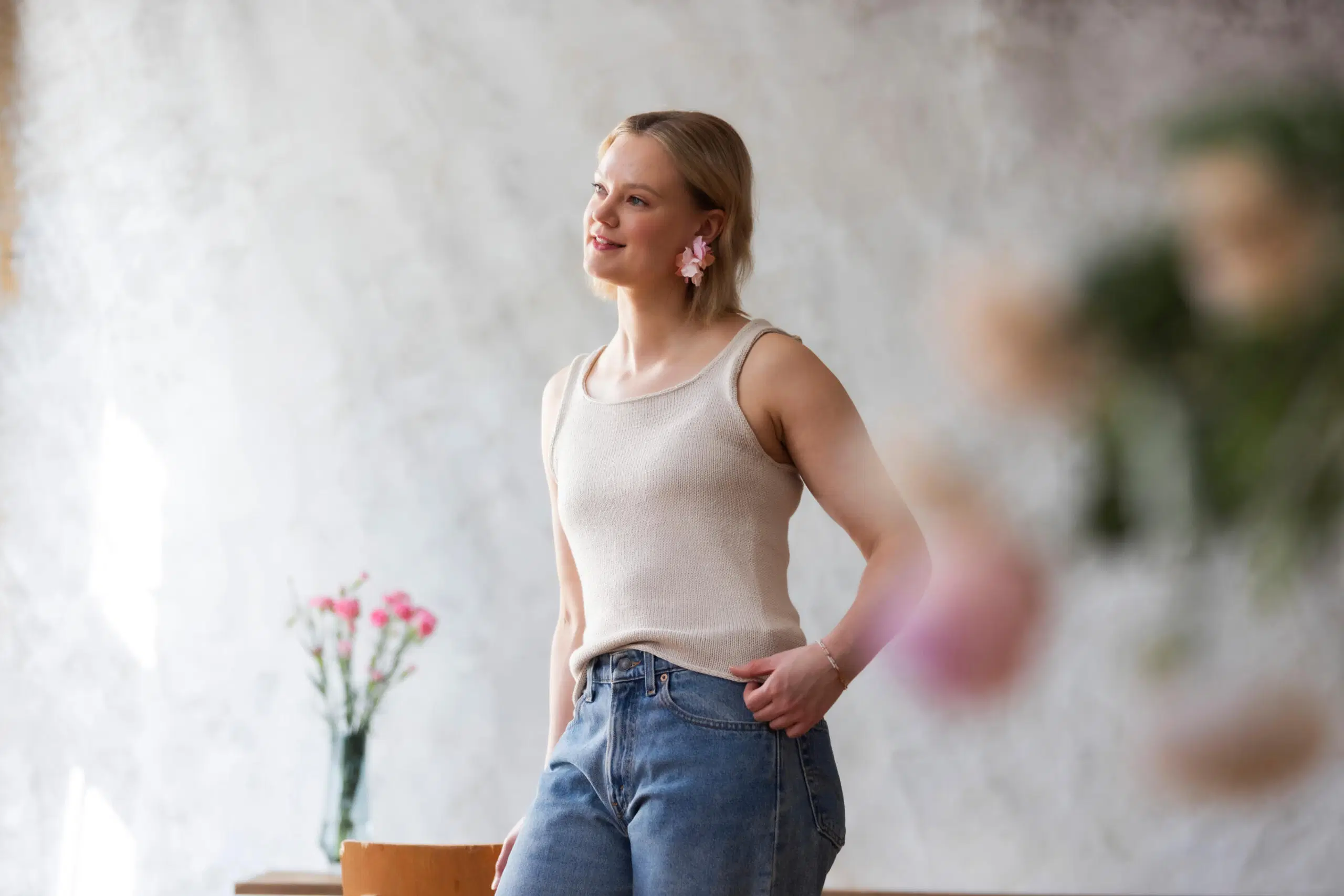 Neulottu Lily-toppi edestä päin mallin päällä, taustalla maljakossa kukkia