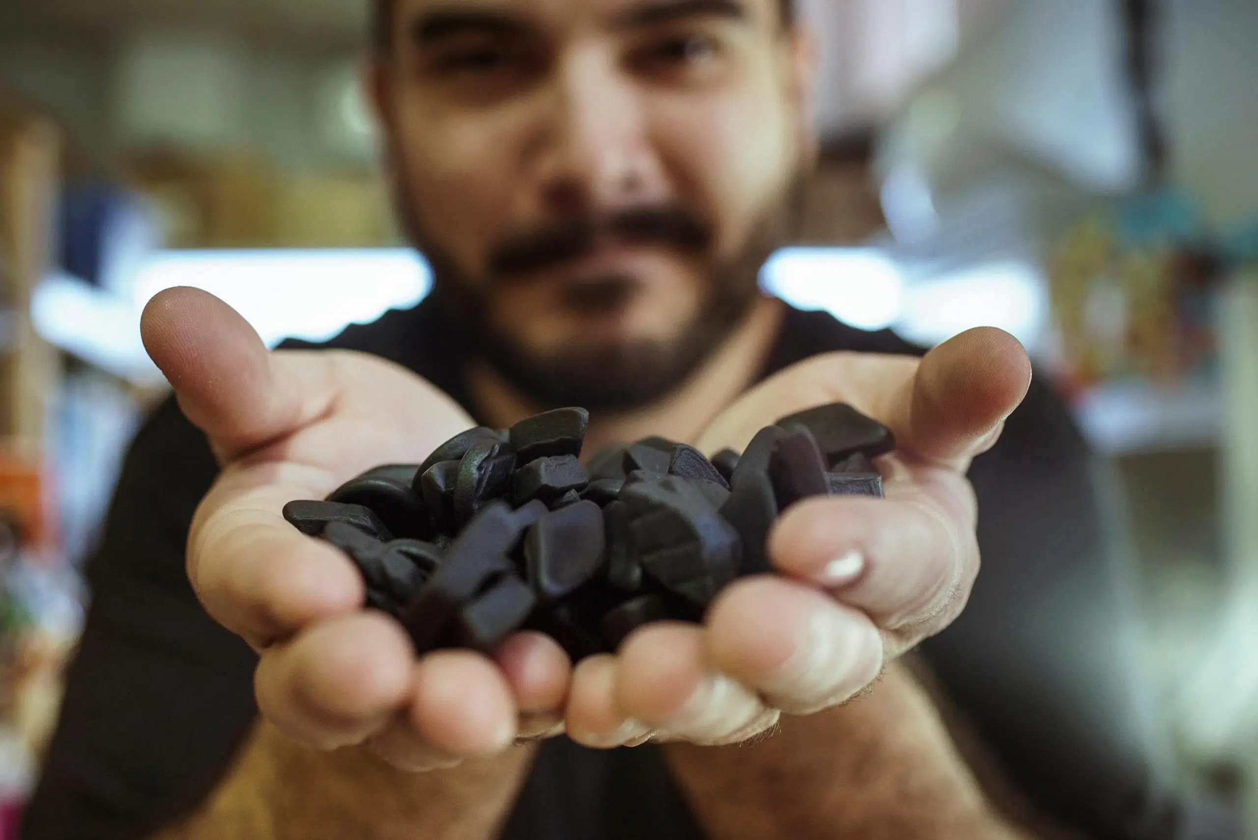 Mies katsoo kameraan käsissään salmiakkia