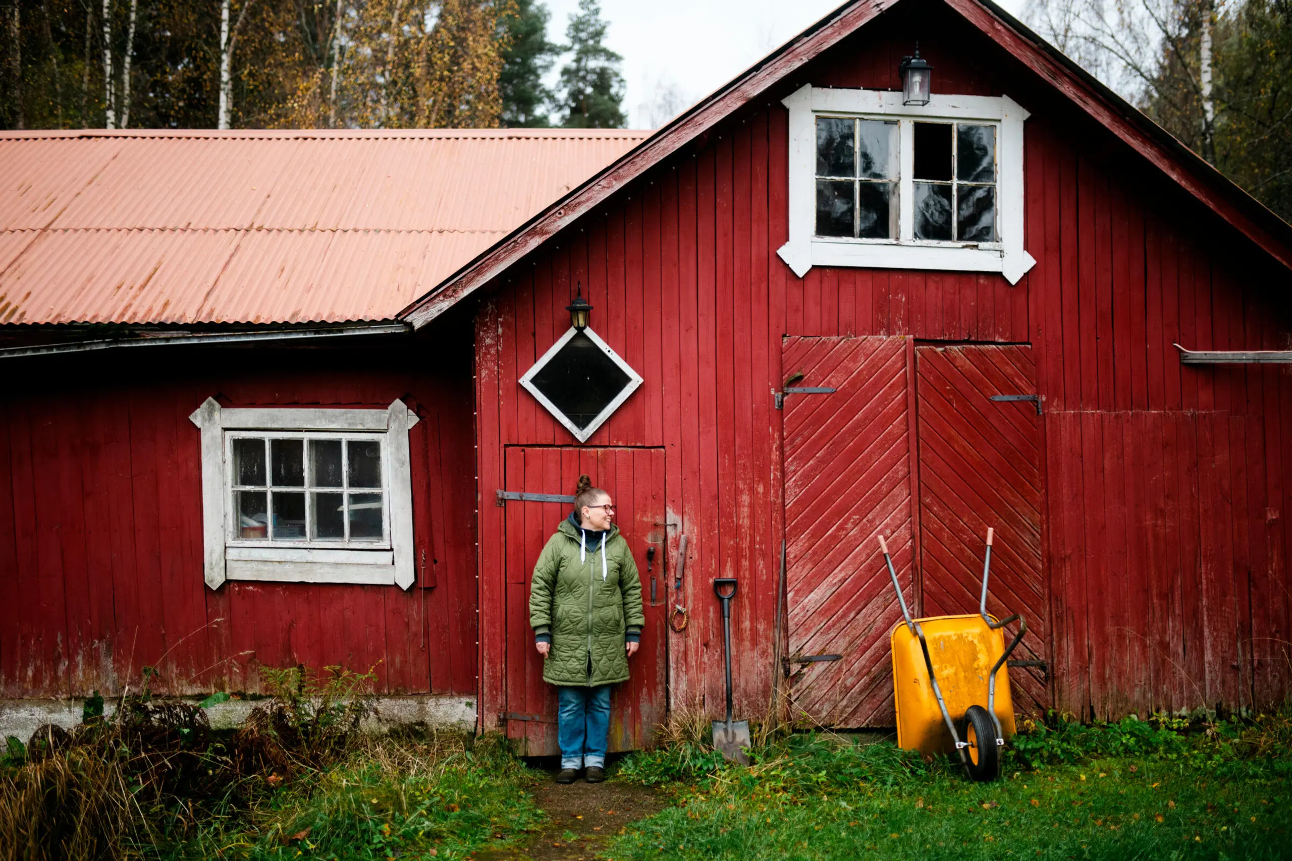 Annulii Koponen seisoo punaisen ladon edessä syksyllä.