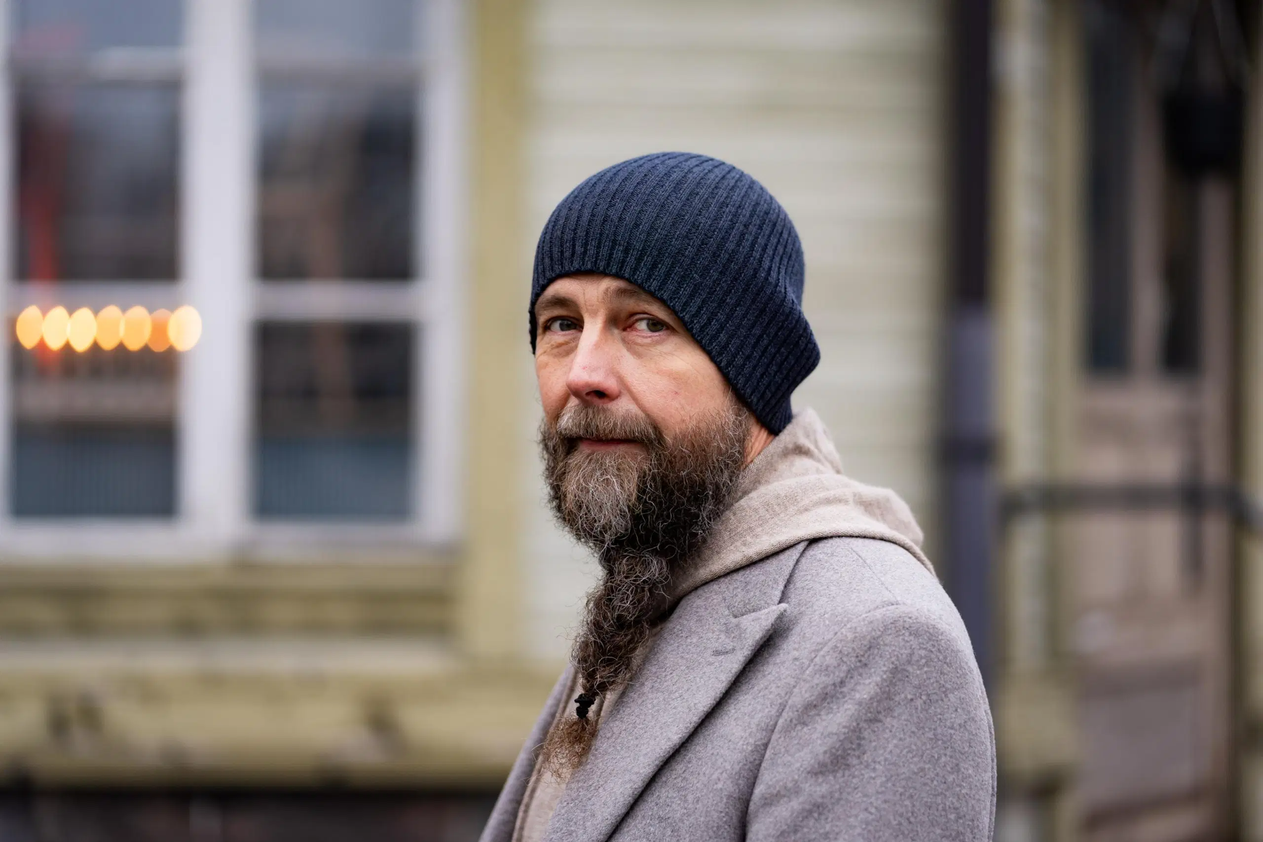 Pipopäinen Tero Vesterinen vaalean puutalon edessä