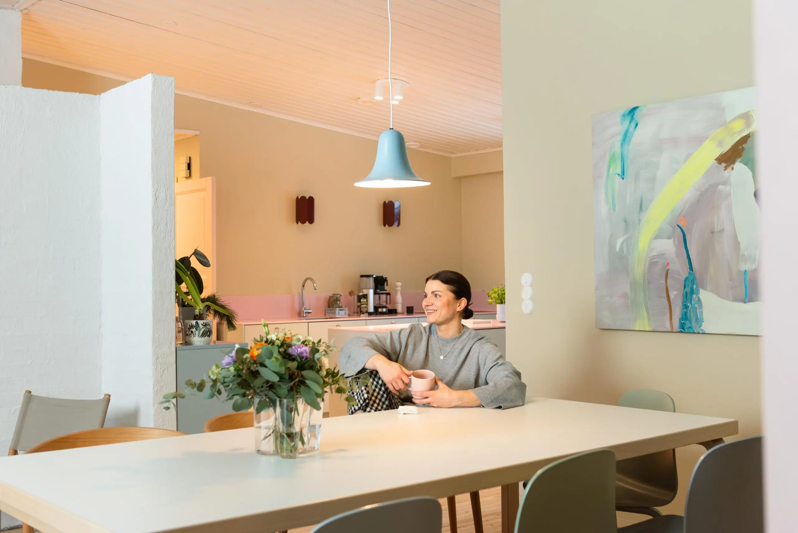 Maru Hautala istuu ruokapöydän ääressä käsissään kahvikuppi.