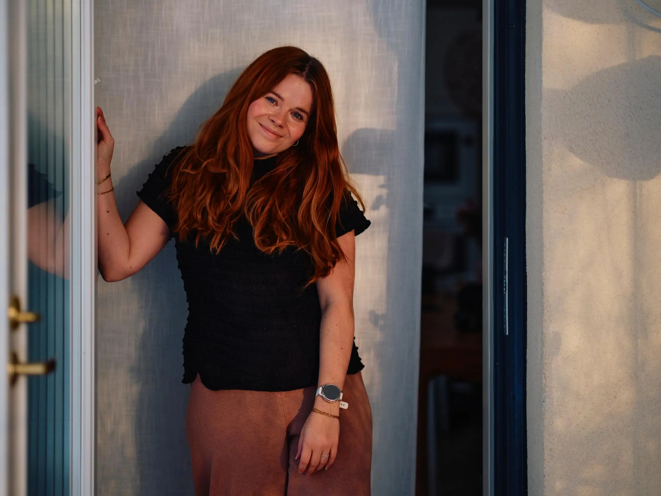 Hymyilevä Salla Salmela seisoo ulko-oven suussa.