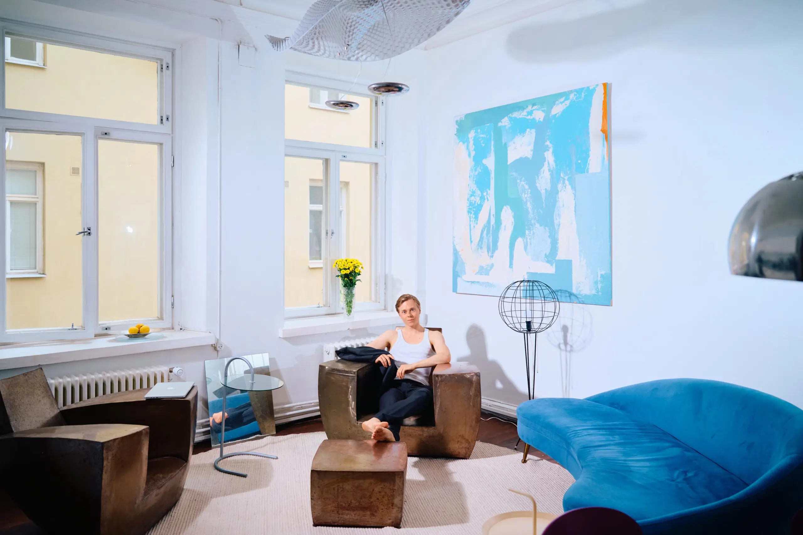 Atte Kilpinen istuu rautanojatuolissa jalat rautaisen sohvapöydän päällä.