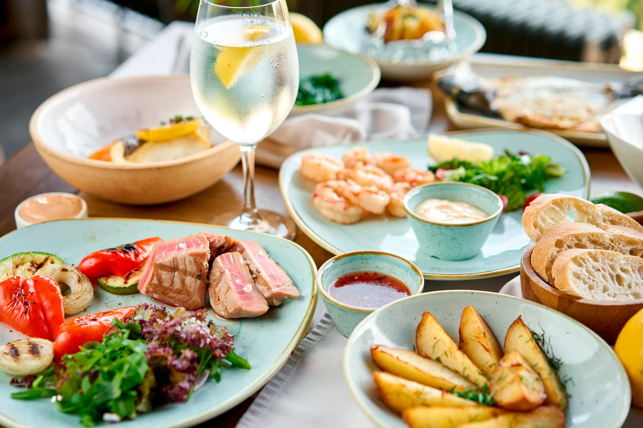 Raskalainen kattaus kalaa, perunoita ja kasviksia. Lasissa on vettä ja sitruunaviipale.