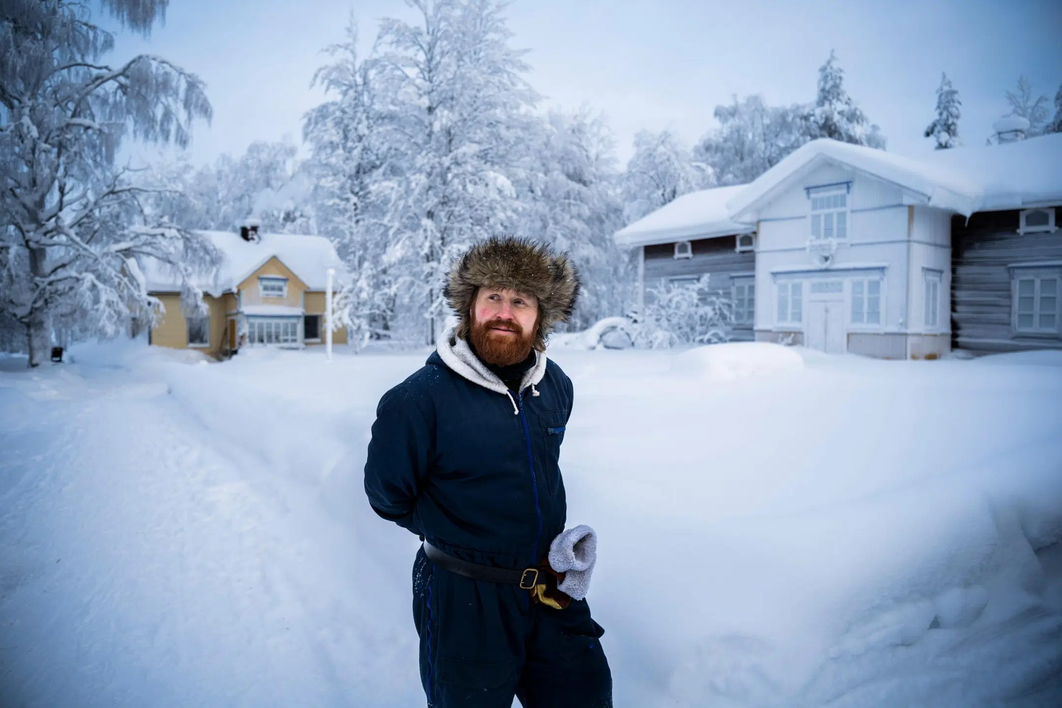 Tommi Manninen seisoo ulkona, takana kotitalo. Maisema on luminen.