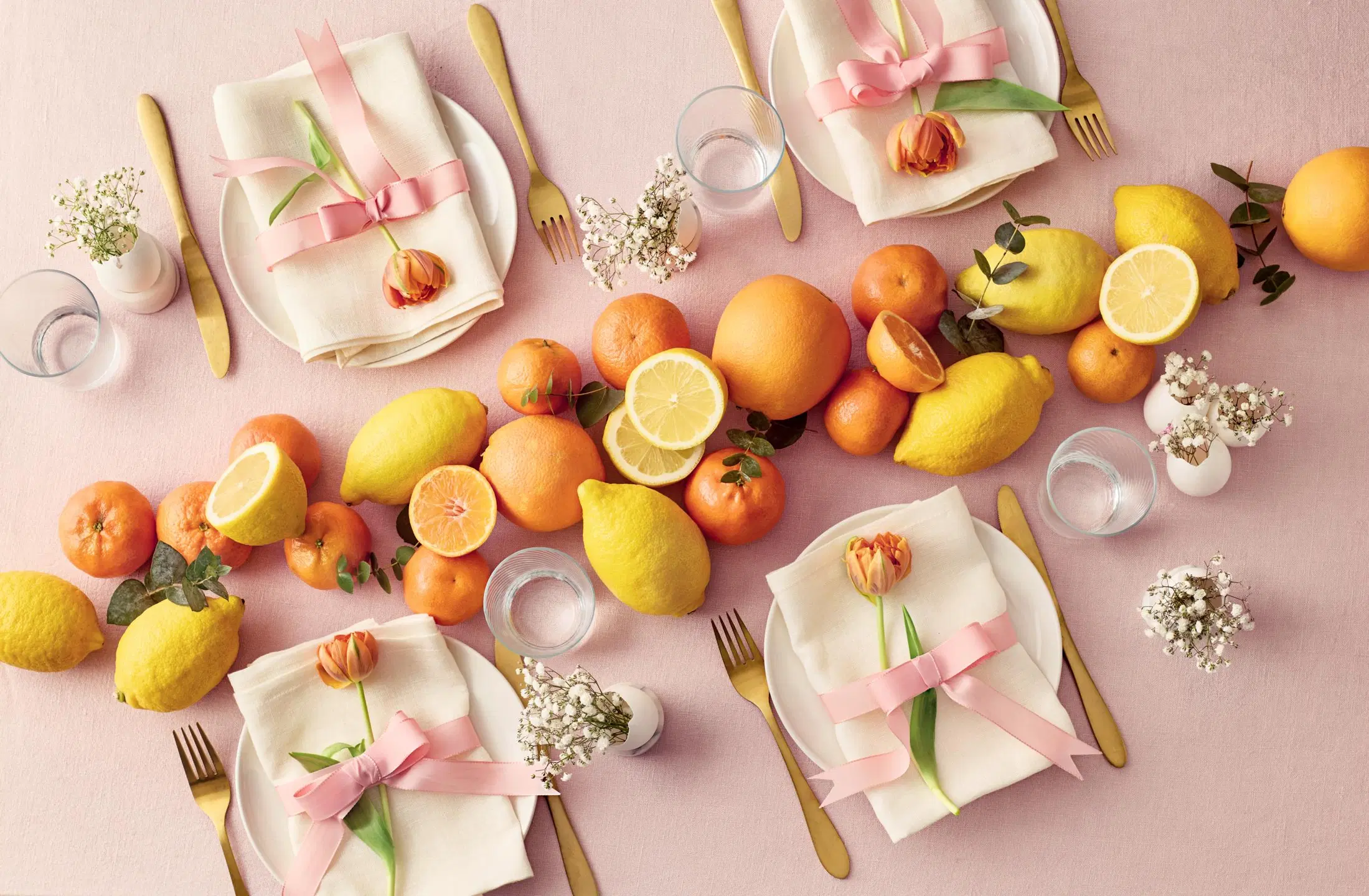 Kattauksessa on pöytäkoriste hedelmistä ja lautasliinat koristeltu tulppaaneilla ja ruseteilla