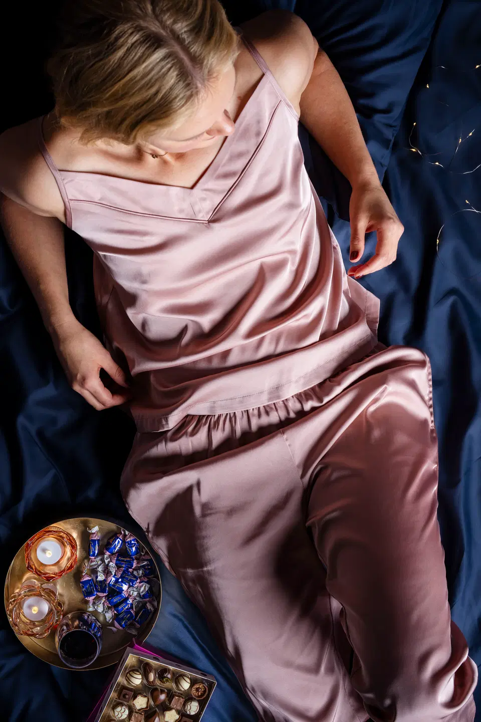 Mallilla päällään satiiniset pyjamahousut ja -toppi, lautasella kynttilöitä ja suklaata
