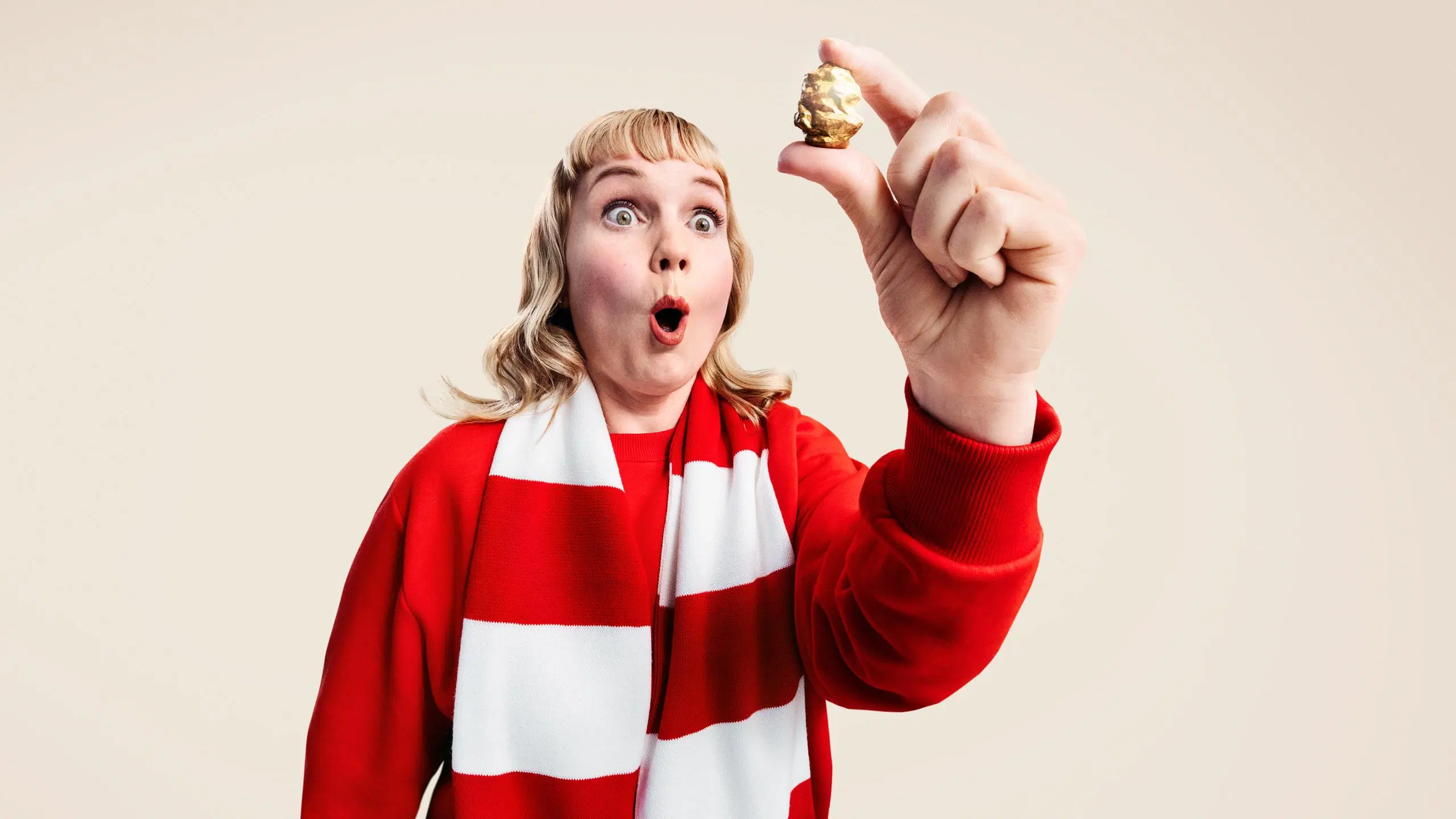 Ällistynyt nainen pitelee sormiensa välissä kultaista rusinaa