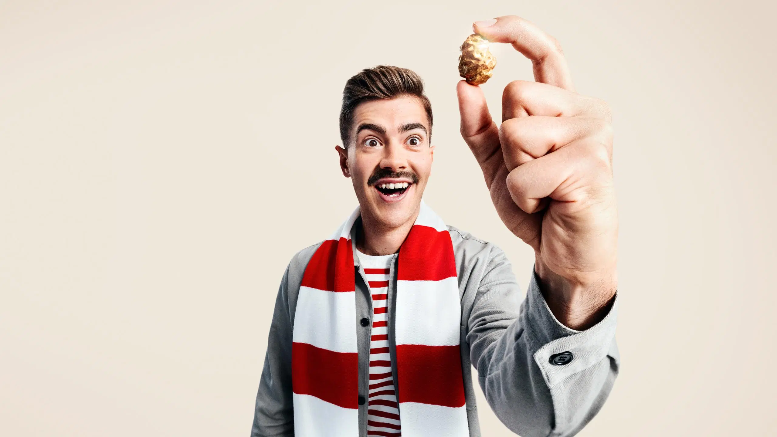 Ällistynyt mies piteee kultaisa rusinaa kahden sormensa välissä