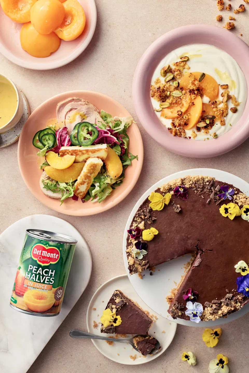 Kuvassa suklaa-persikkakakku, persikkainen jogurttiannos ja kana-persikkasalaatti sekä tölkki Del Monte persikanpuolikkaita mehussa