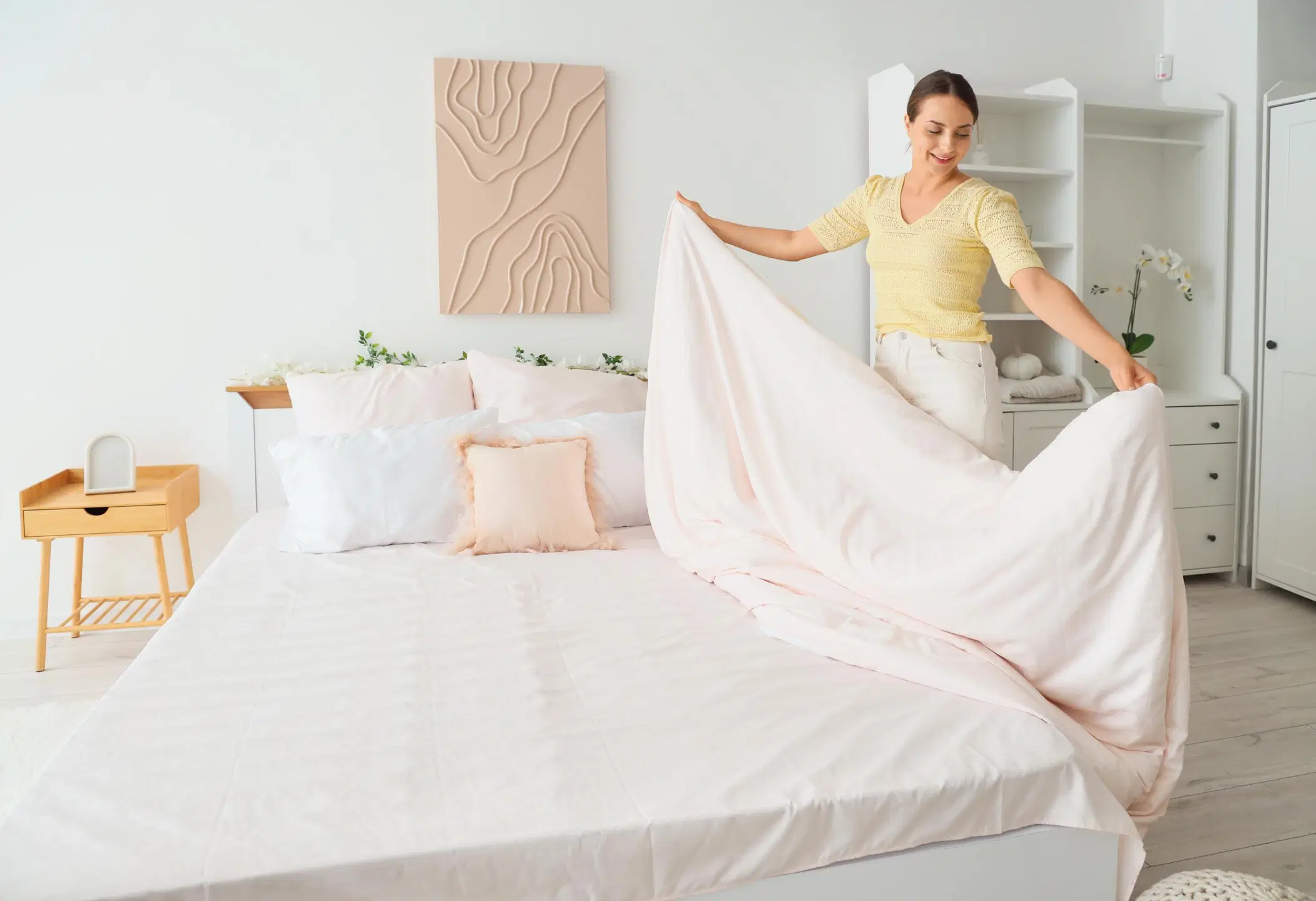 Nainen purkaa petausta sängystä.