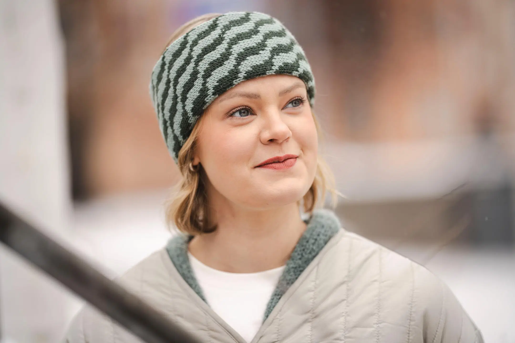 Nainen, jonka päässä on raidallinen vihreä neulepanta.