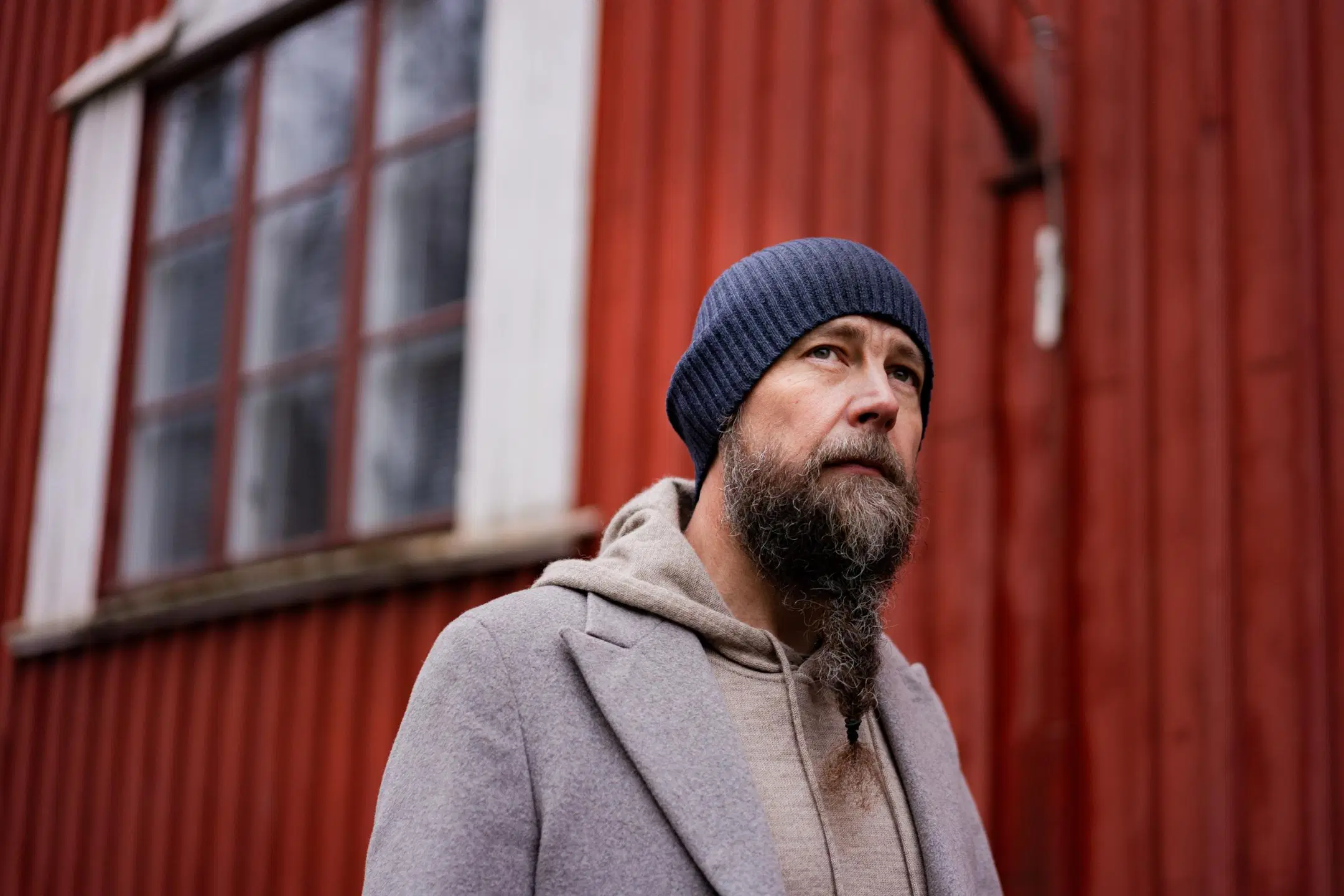 Pipopäinen Tero Vesterinen punaisen puutalon edessä