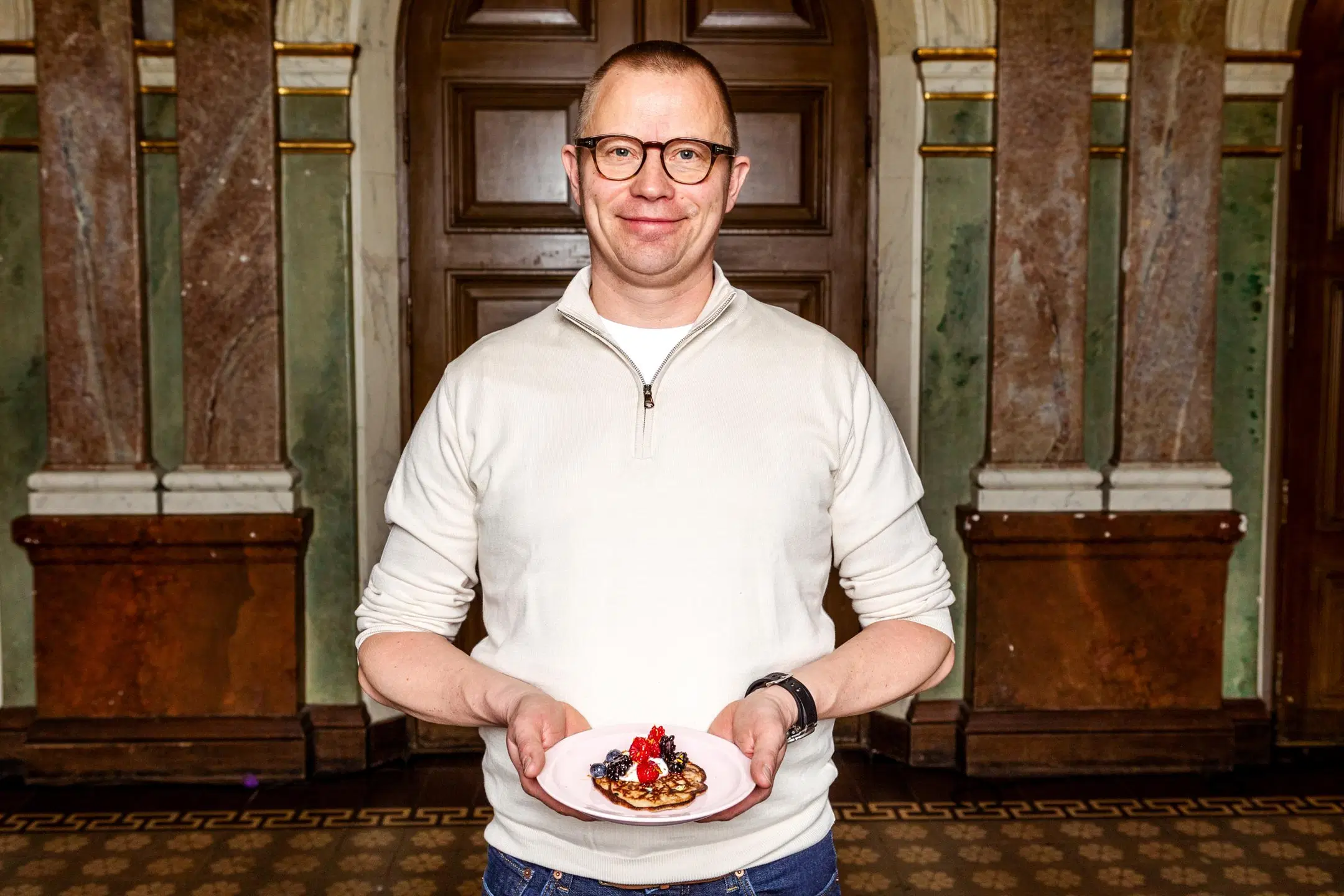 Samuli Wirgentius käsissään lautanen, jolla on lettu kermavaahdolla ja marjoilla