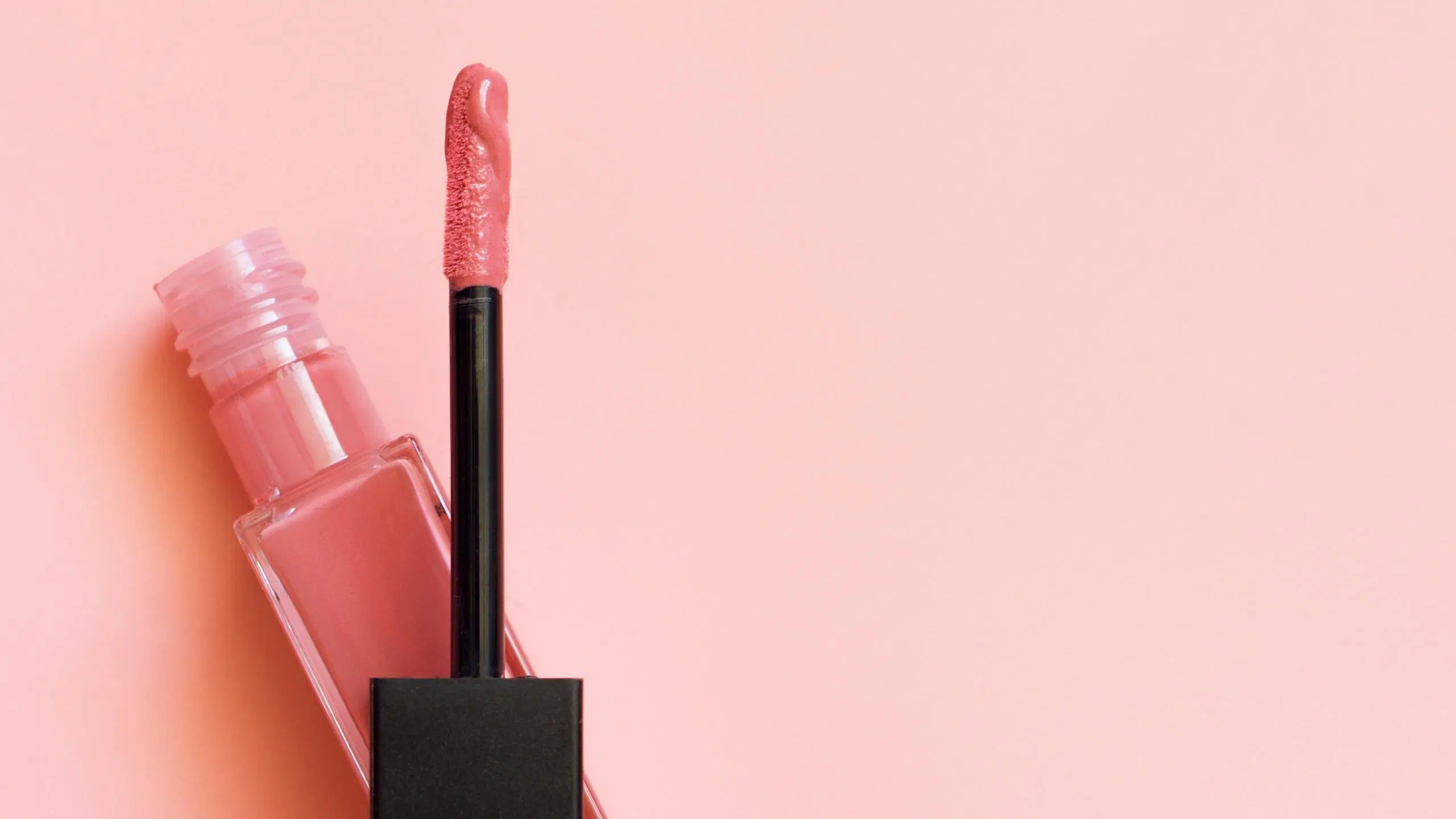 Vaaleanpunainen huulikiilto vaaleanpunaisella taustalla