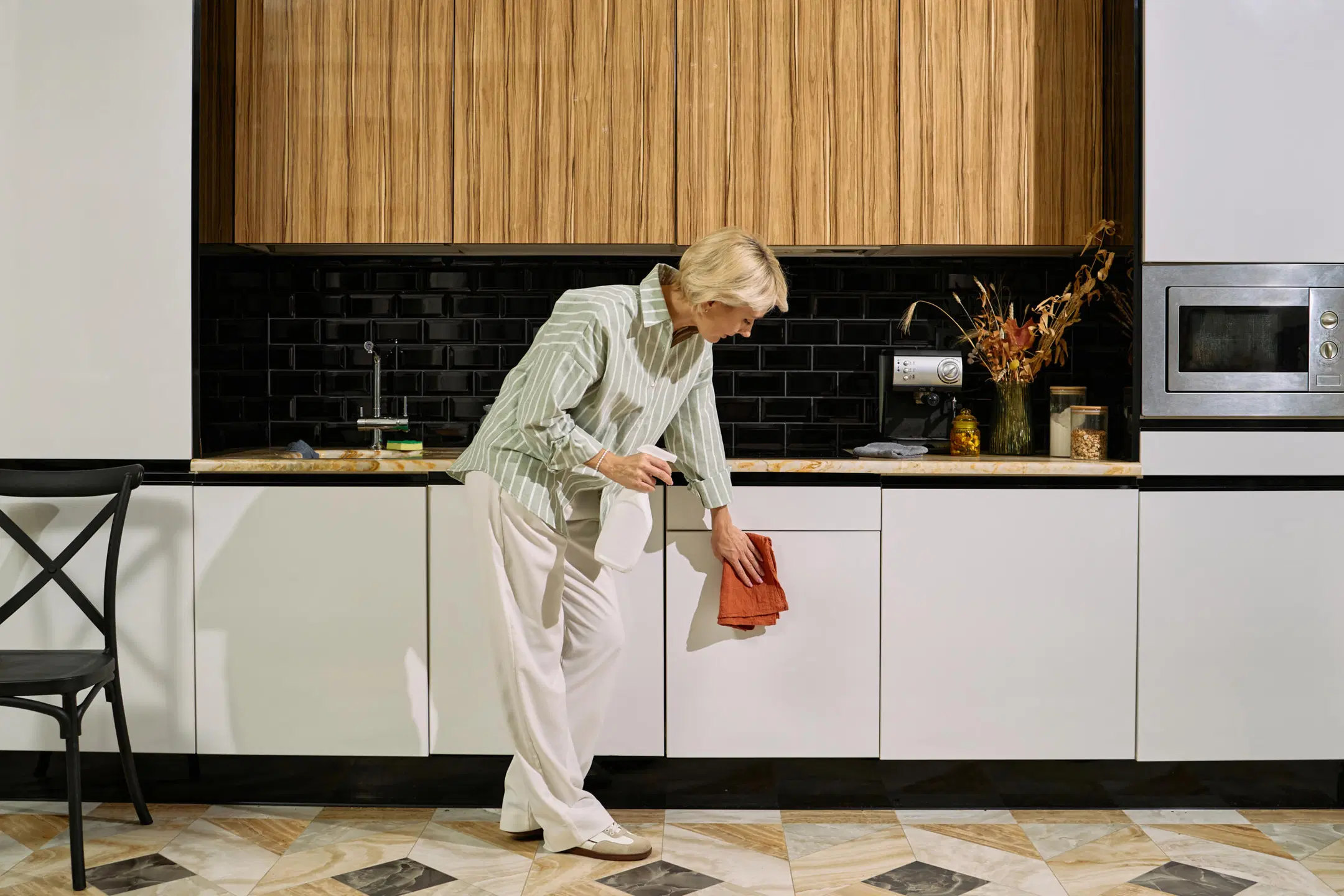 Nainen pyyhkii keittiön kaappien ovia