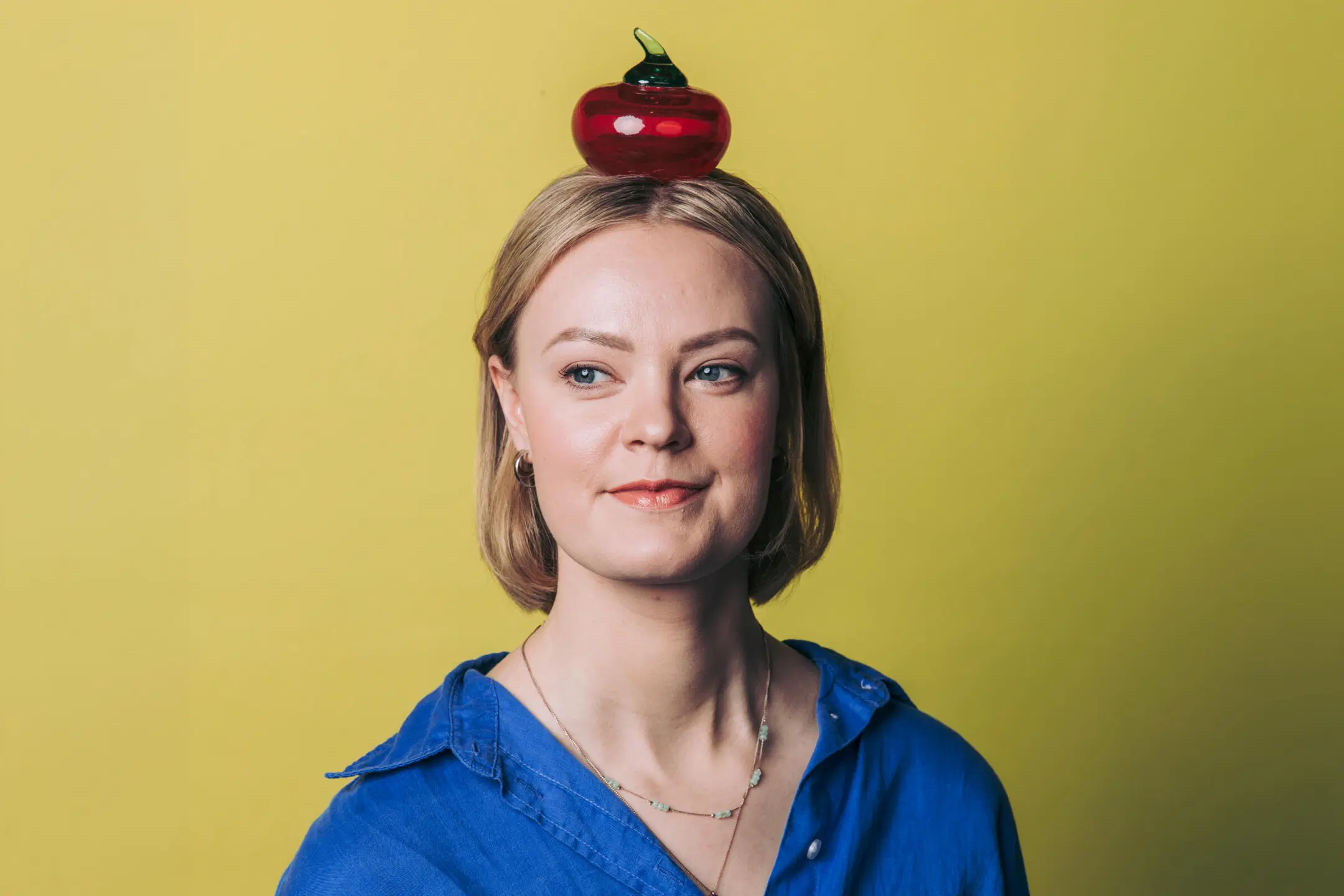 Nainen katsoo vasemmalle, lasiomena pään päällä..