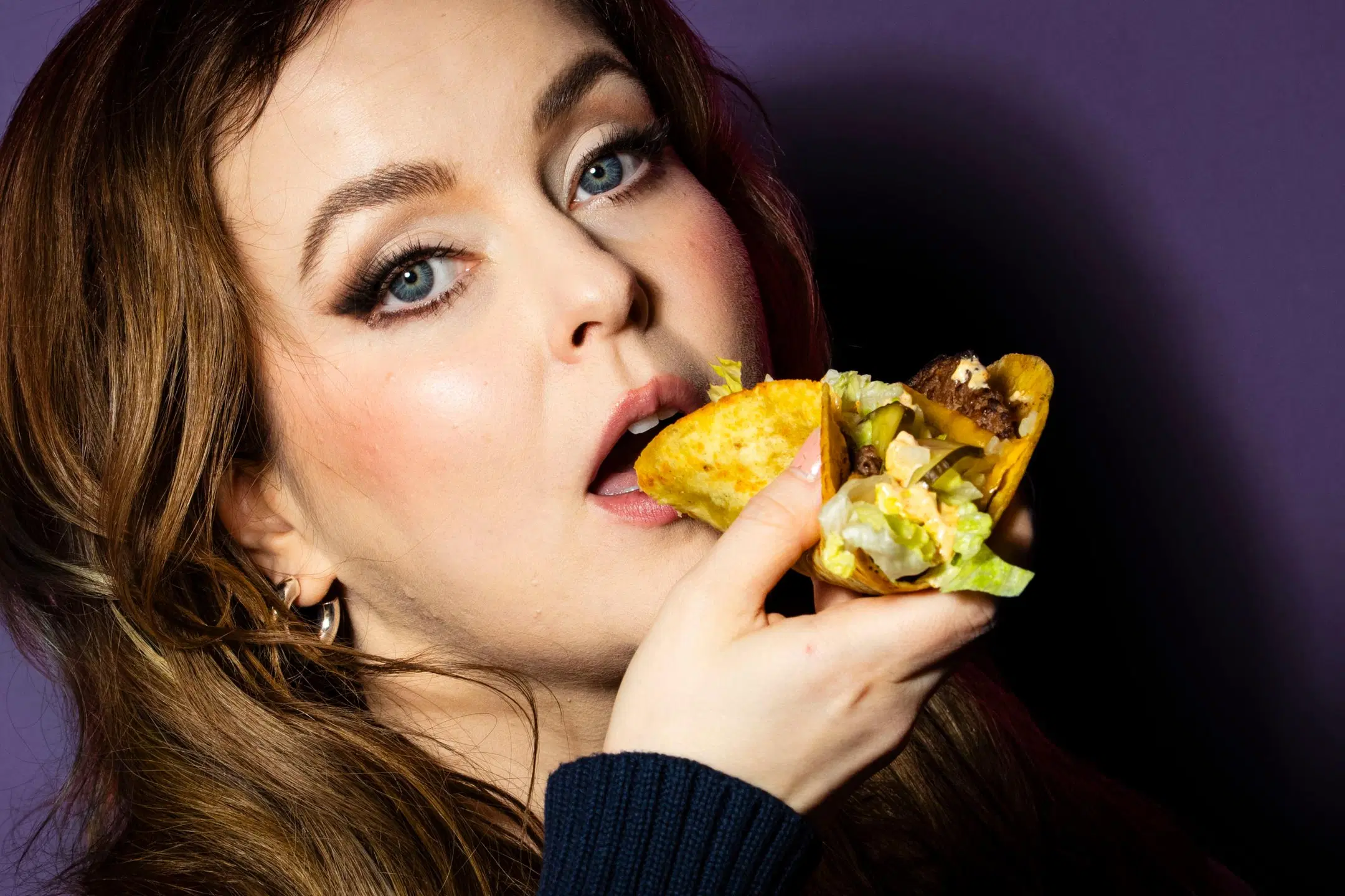 Nainen haukkaa burgeritacoa