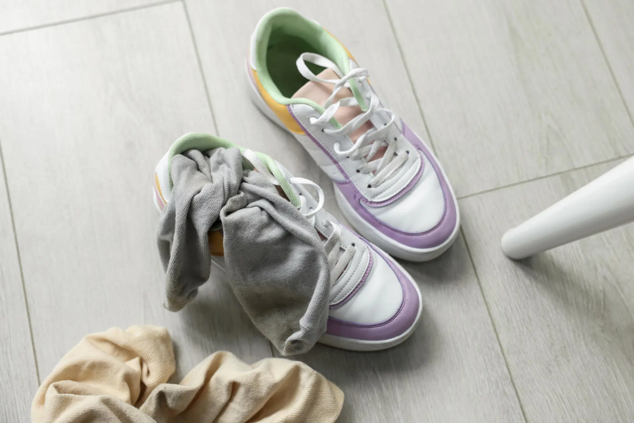 Valkeat tennarit ja kahdet käytetyt sukat lattialla.