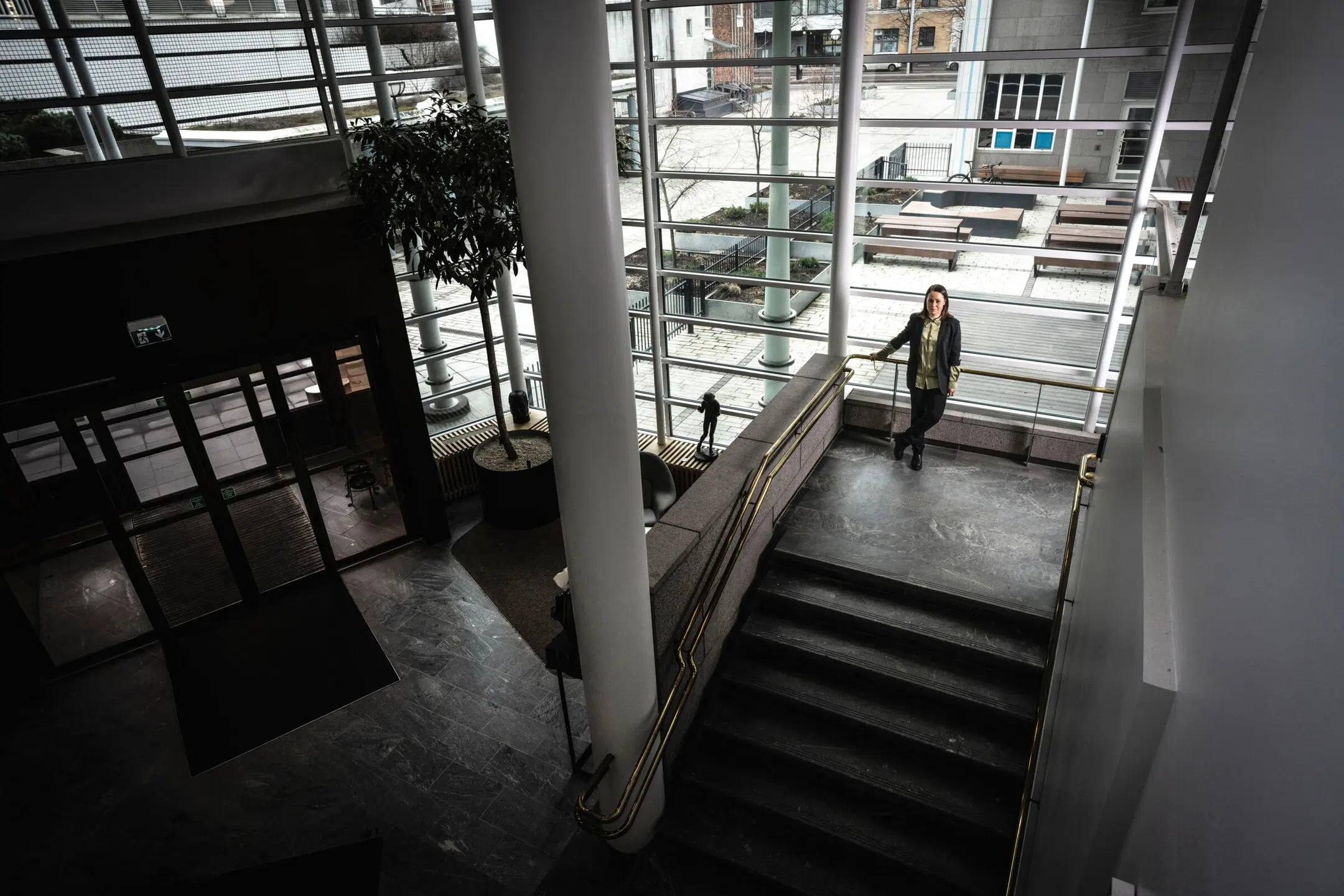Nainen seisoo suuryrityksen aulatilan portaikolla