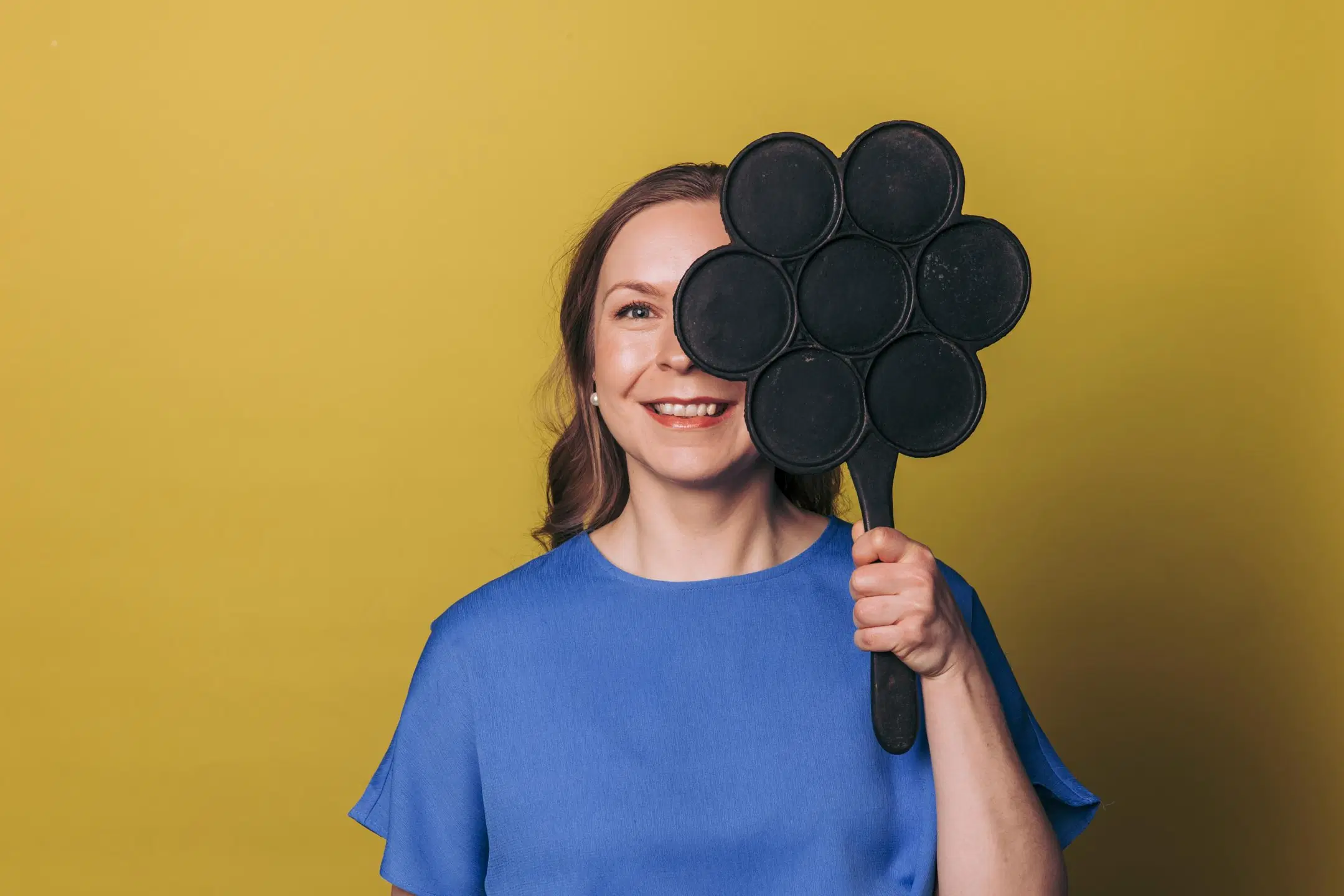 Outi Vartiainen, joka pitää kasvojensa edessä lettupannua.