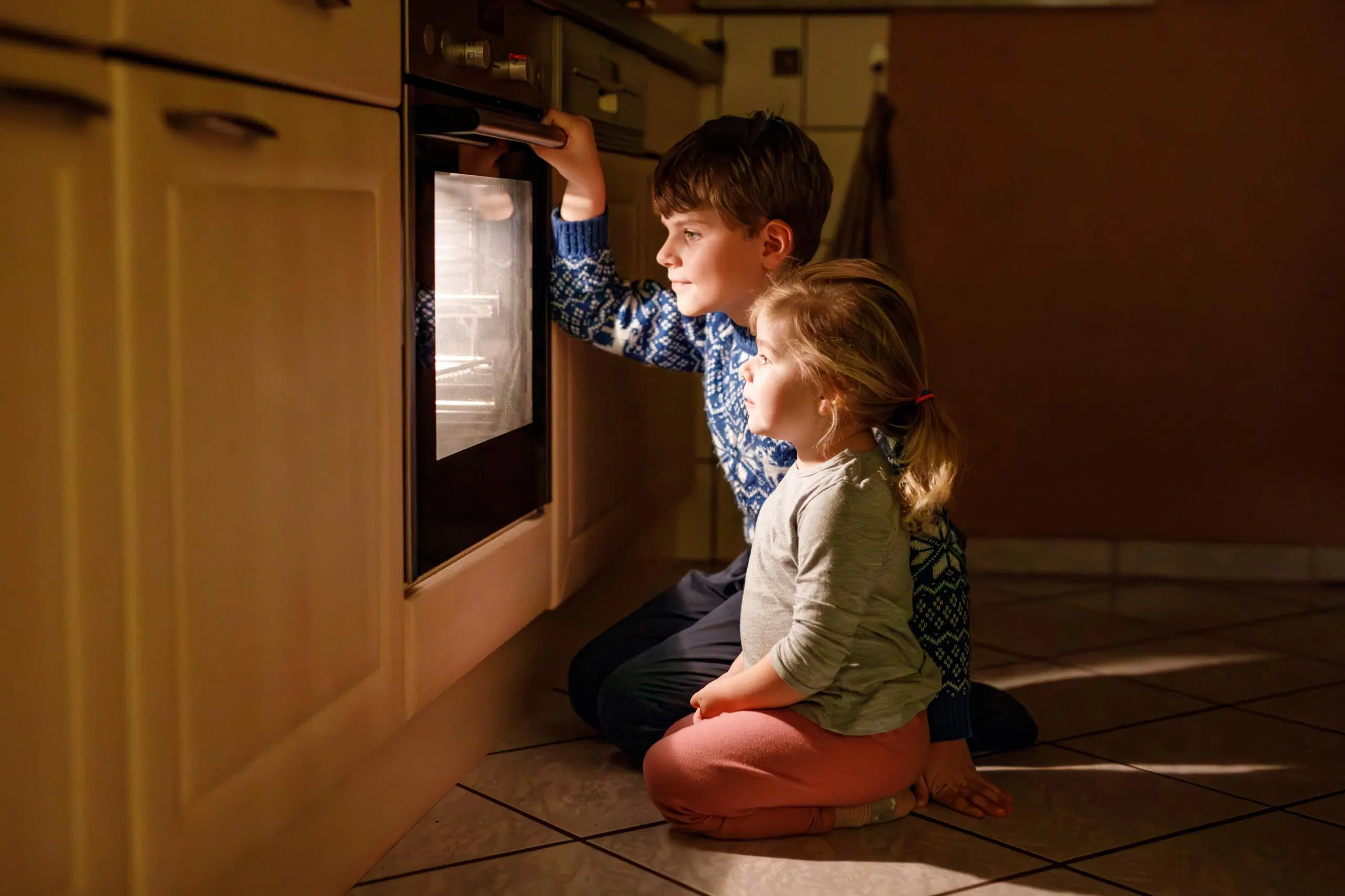 Lapset katselevat uunissa valmistuvaa ruokaa.