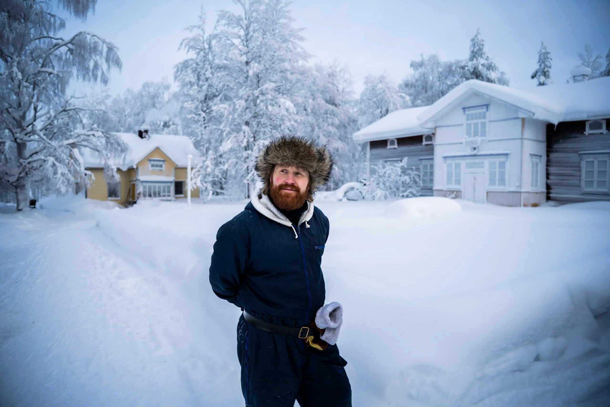 Tommi Manninen seisoo ulkona, takana kotitalo. Maisema on luminen.