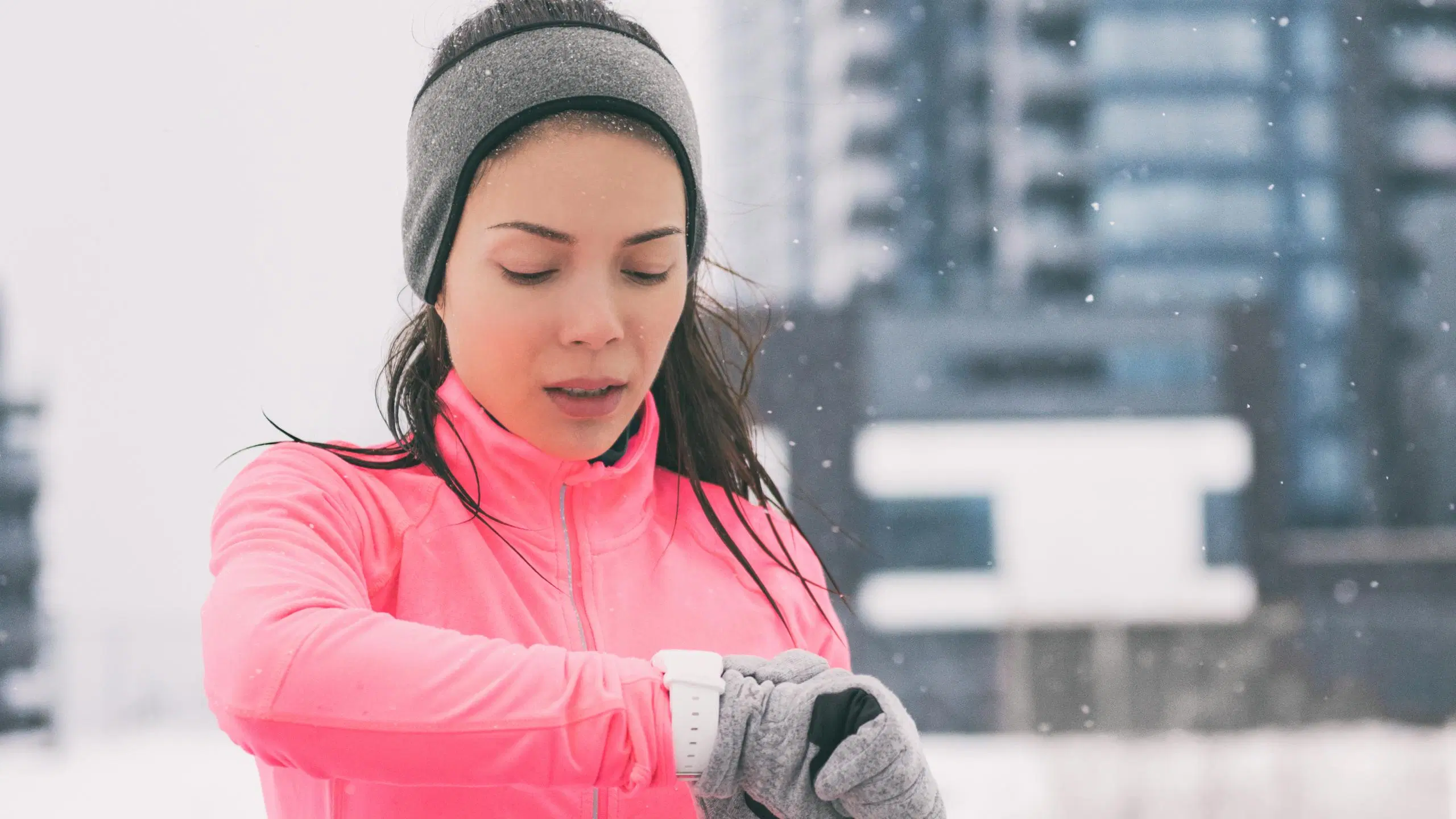 Talvisäässä ulkoileva nainen katsoo älykelloa