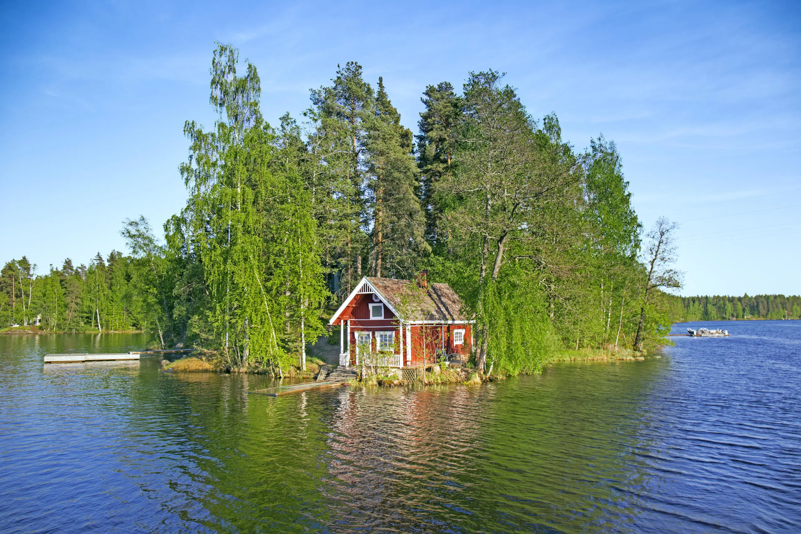 Kesäinen kuva saarella sijaitsevasta mökistä 