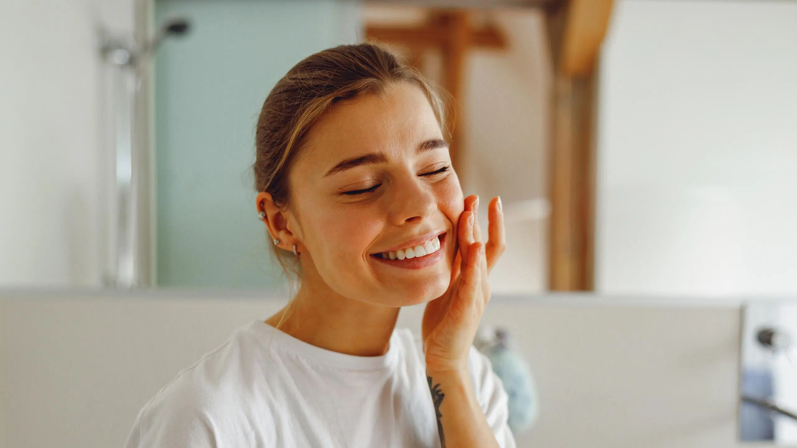 Nainen levittää ihonhoitotuotetta sormilla kasvoille.