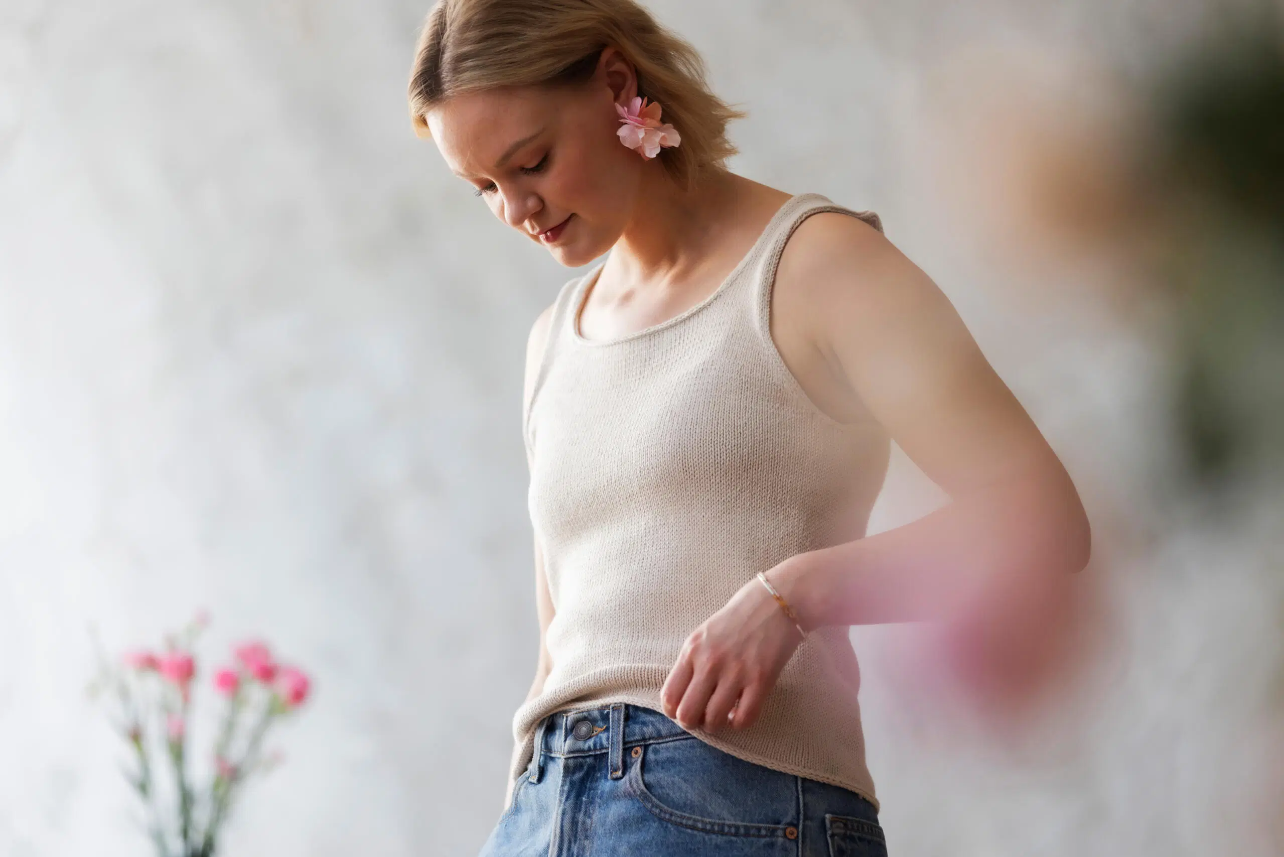 Vaalean värinen, neulottu Lily-toppi naisen yllä