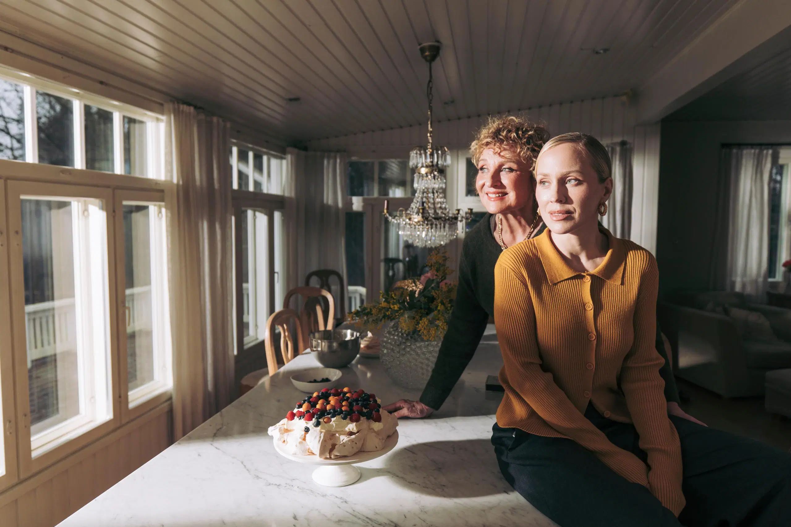 Hanna Sumari ja Kirsikka Simberg pitkän pöydän äärellä. Pöydällä on marjoilla koristeltu pavlova.