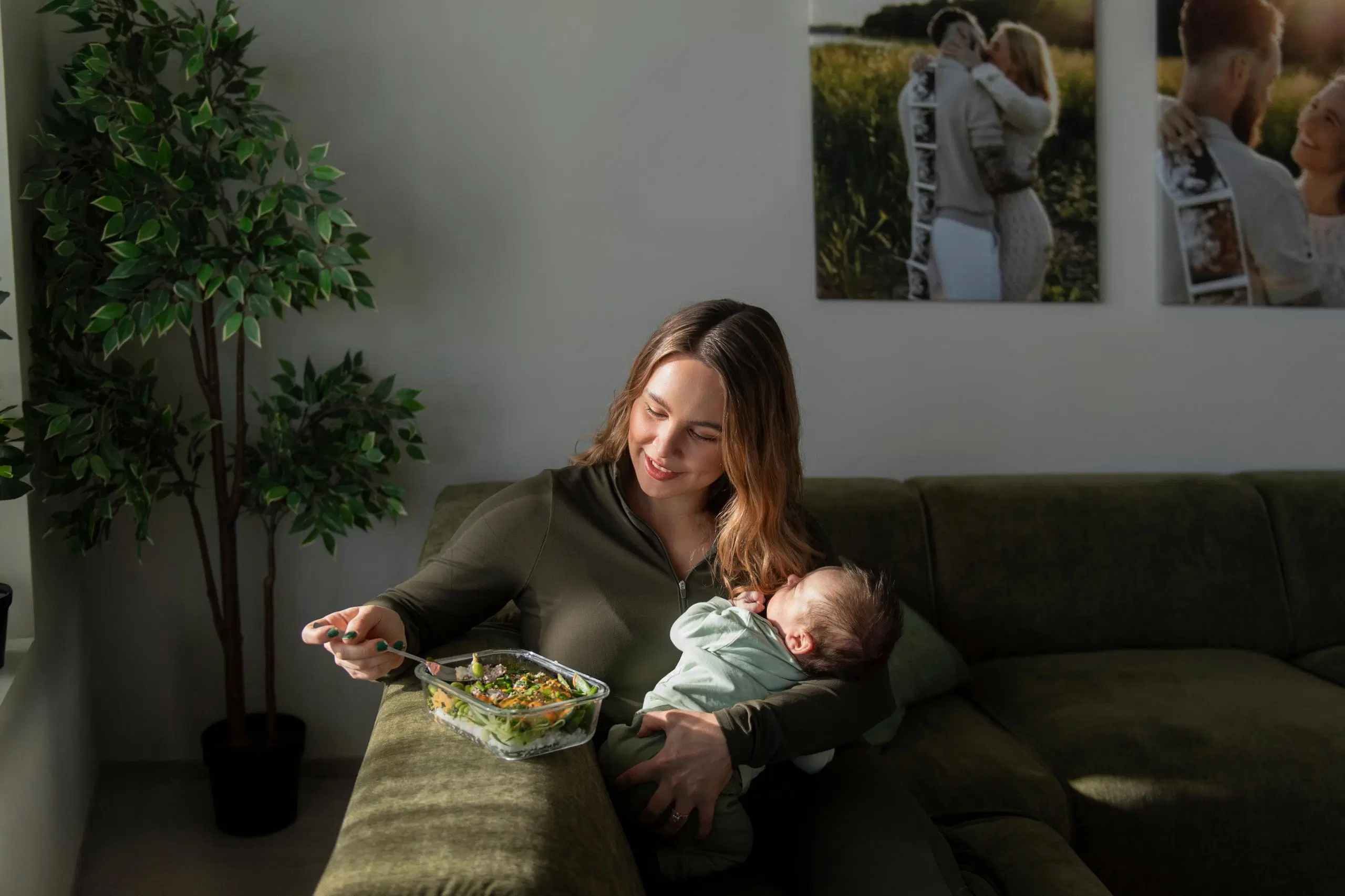 Eveliina Uosukainen istuu sohvalla vauva sylissä ja syö lasiastiasta ruokaa.